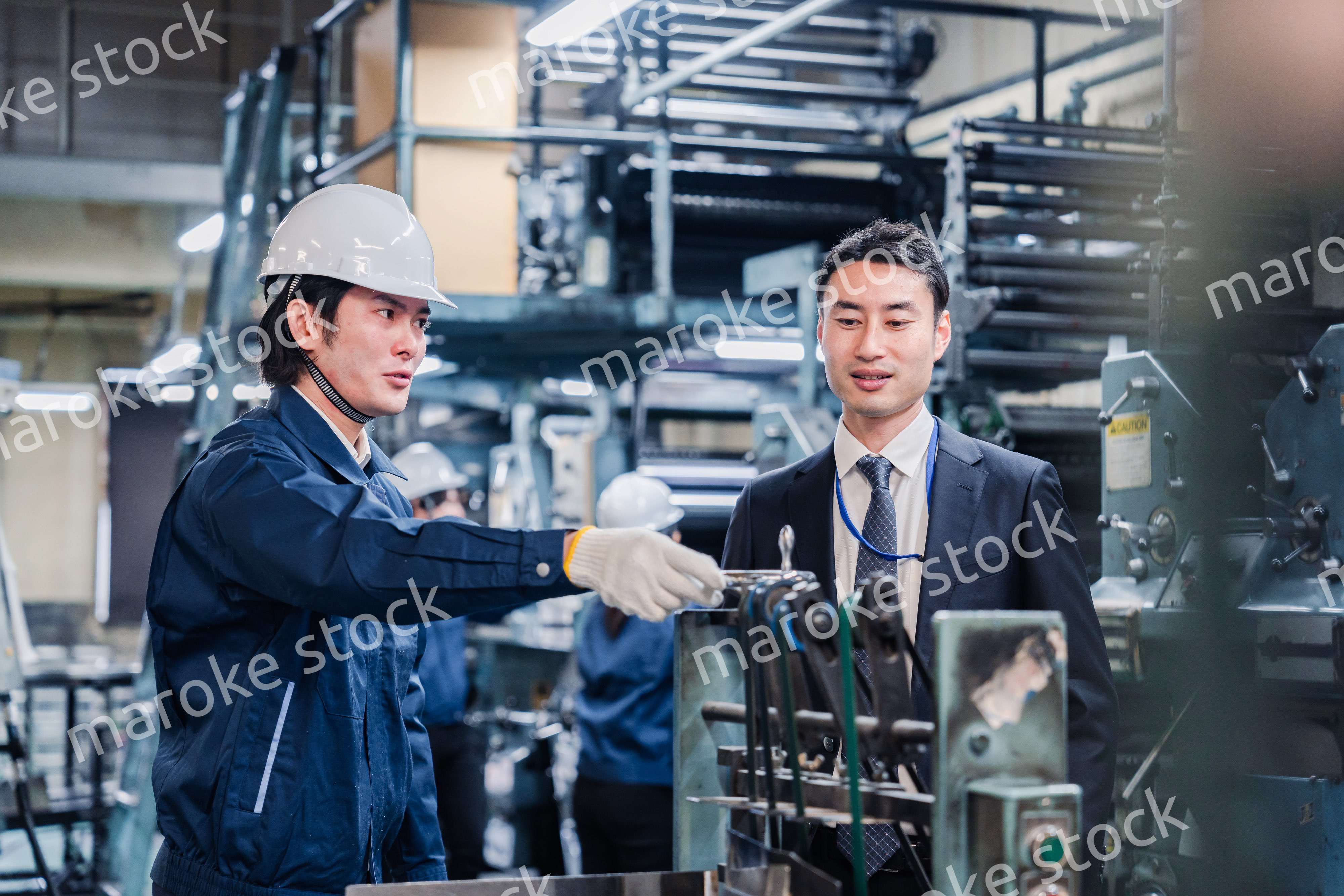 機械の前で話をする営業マンと労働者