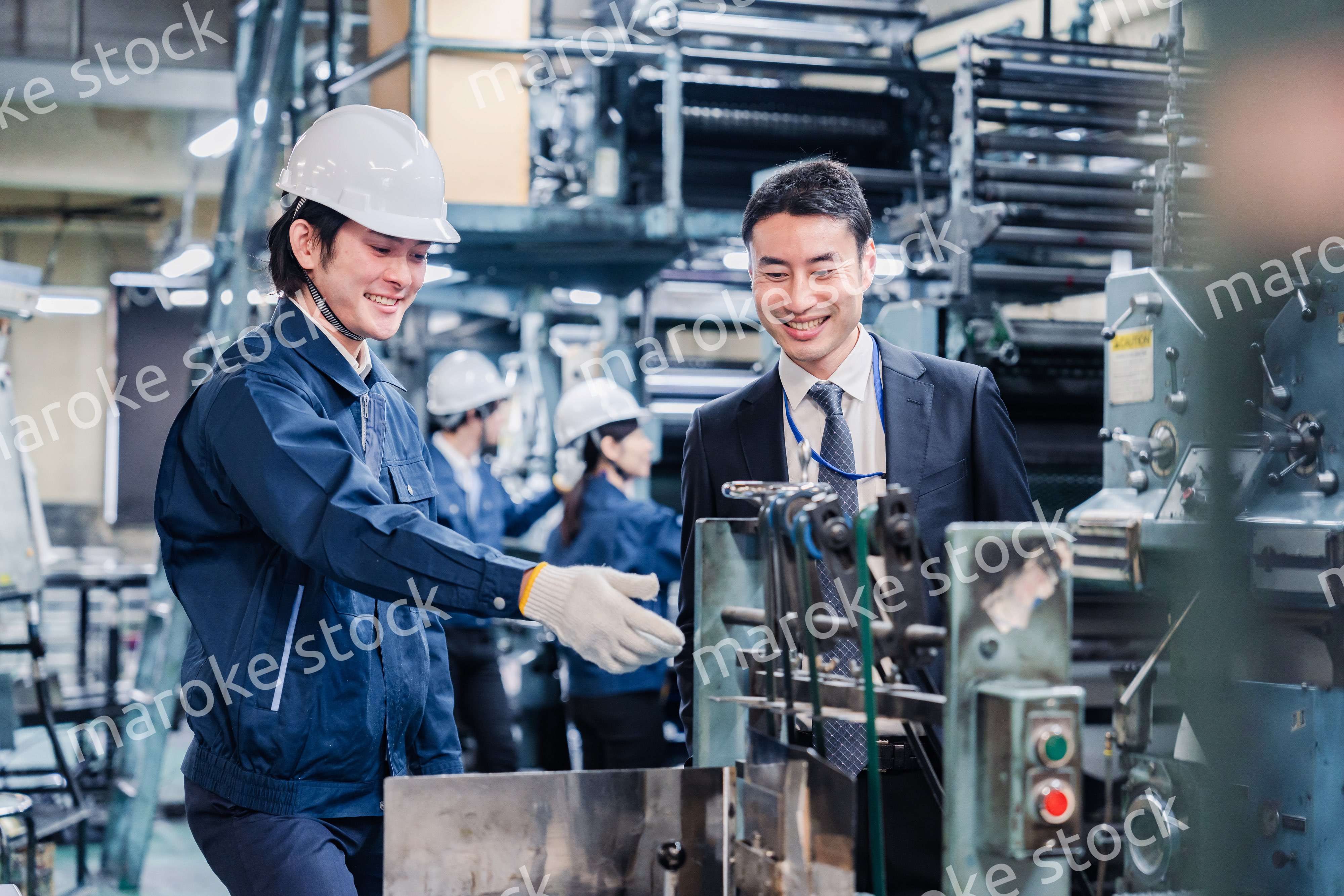 機械の前で話をする営業マンと労働者