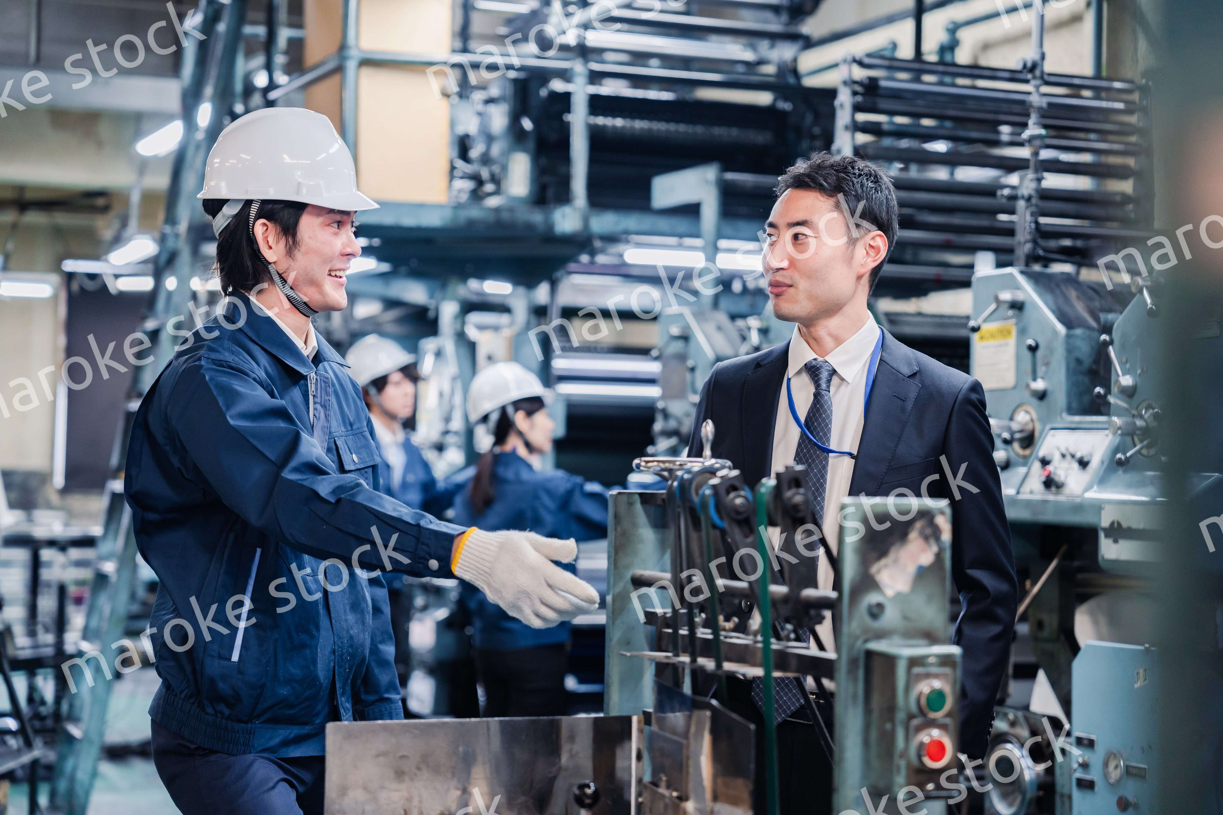 機械の前で話をする営業マンと労働者