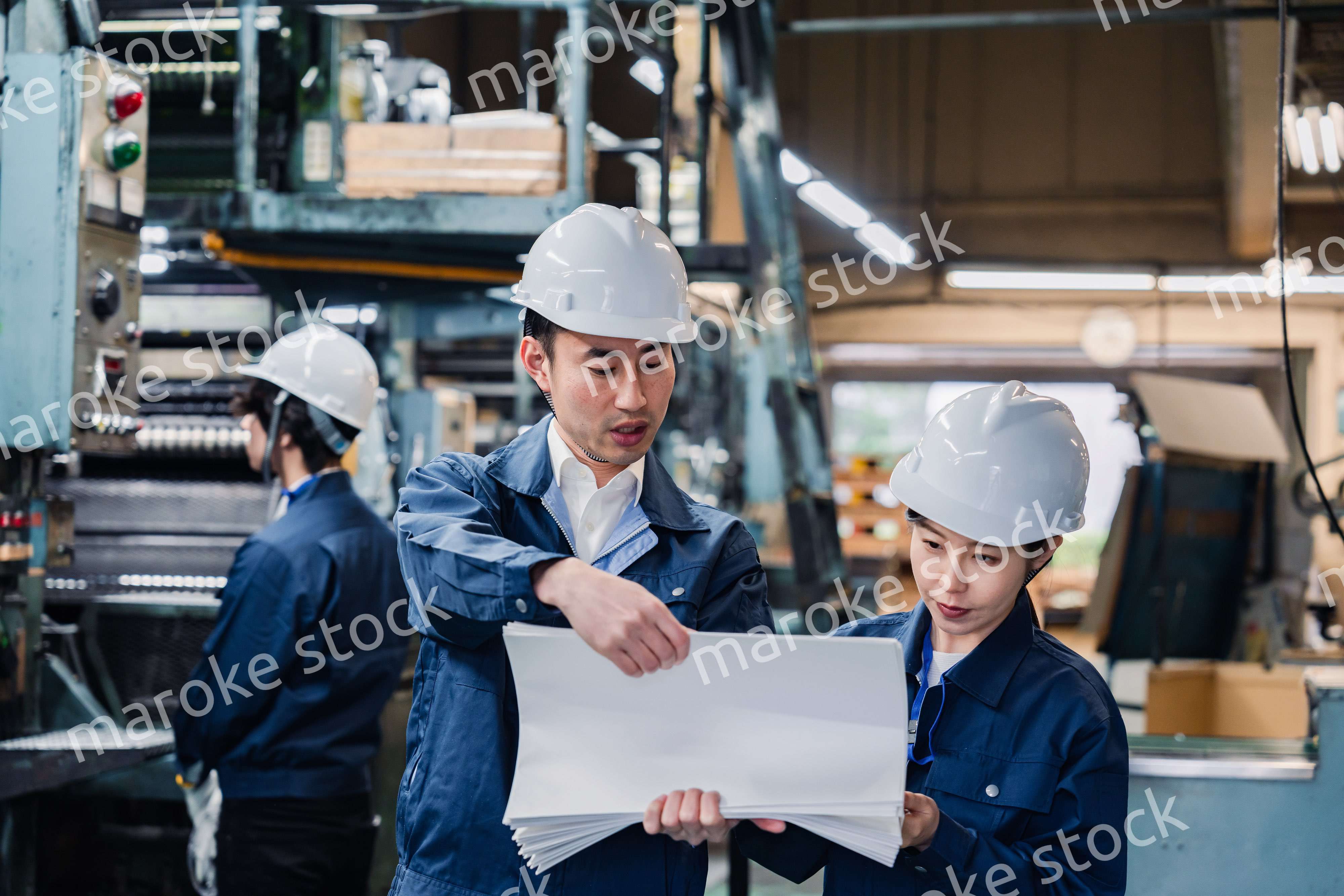 大量の紙資料を確認する工場スタッフ