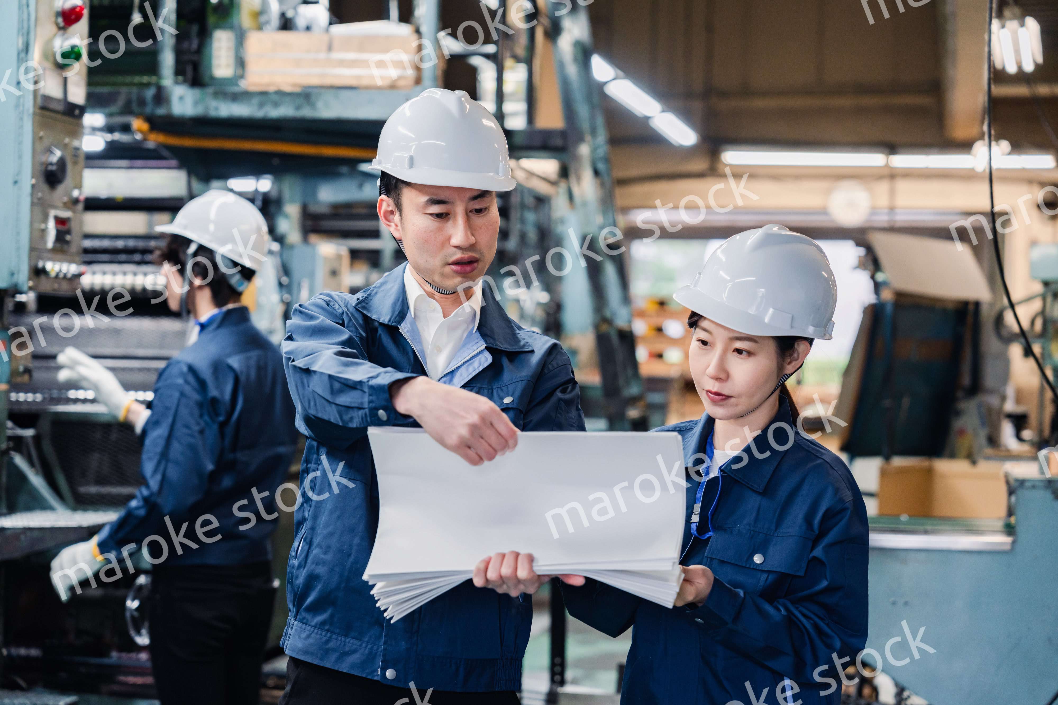 大量の紙資料を確認する工場スタッフ