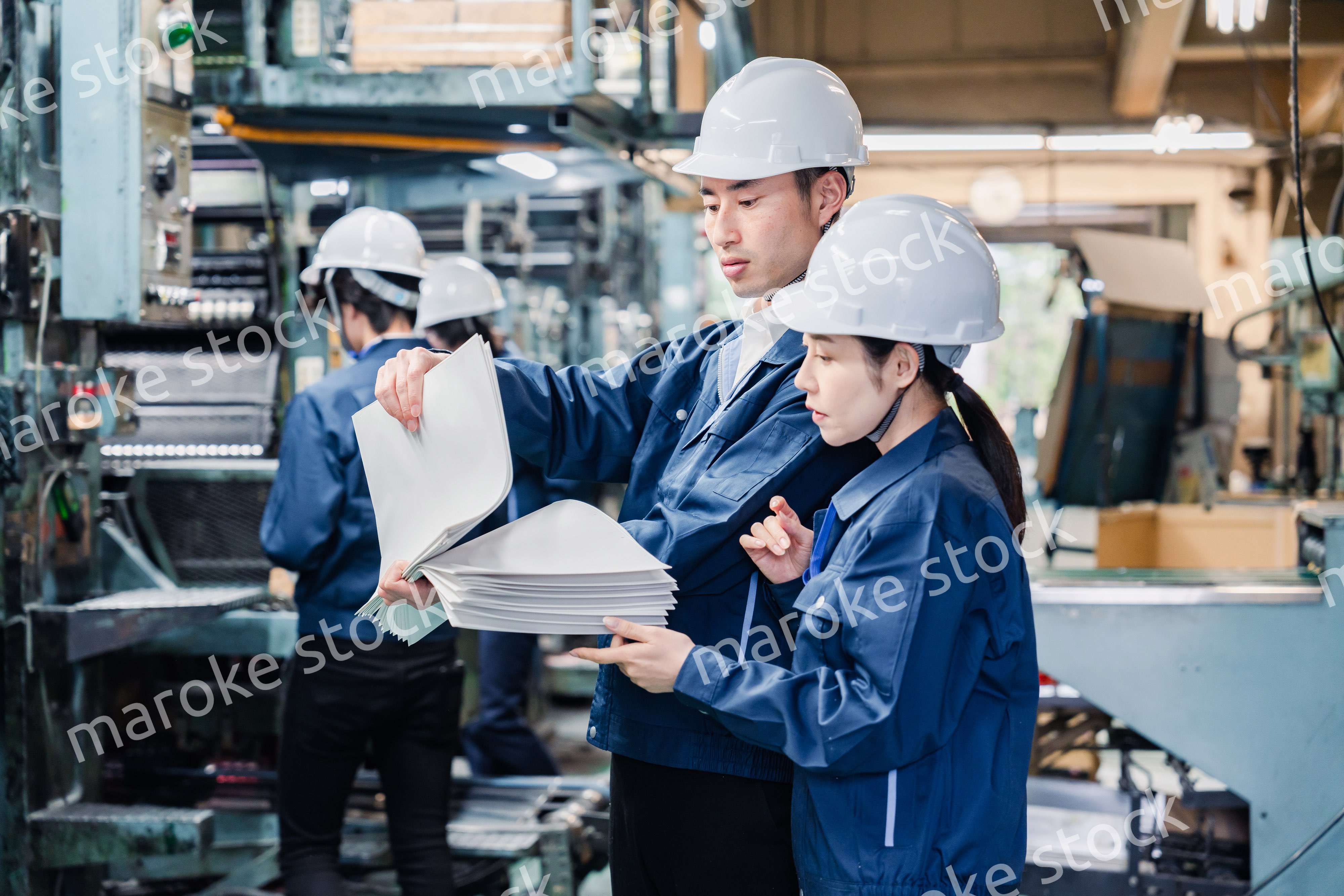 大量の紙資料を確認する工場スタッフ