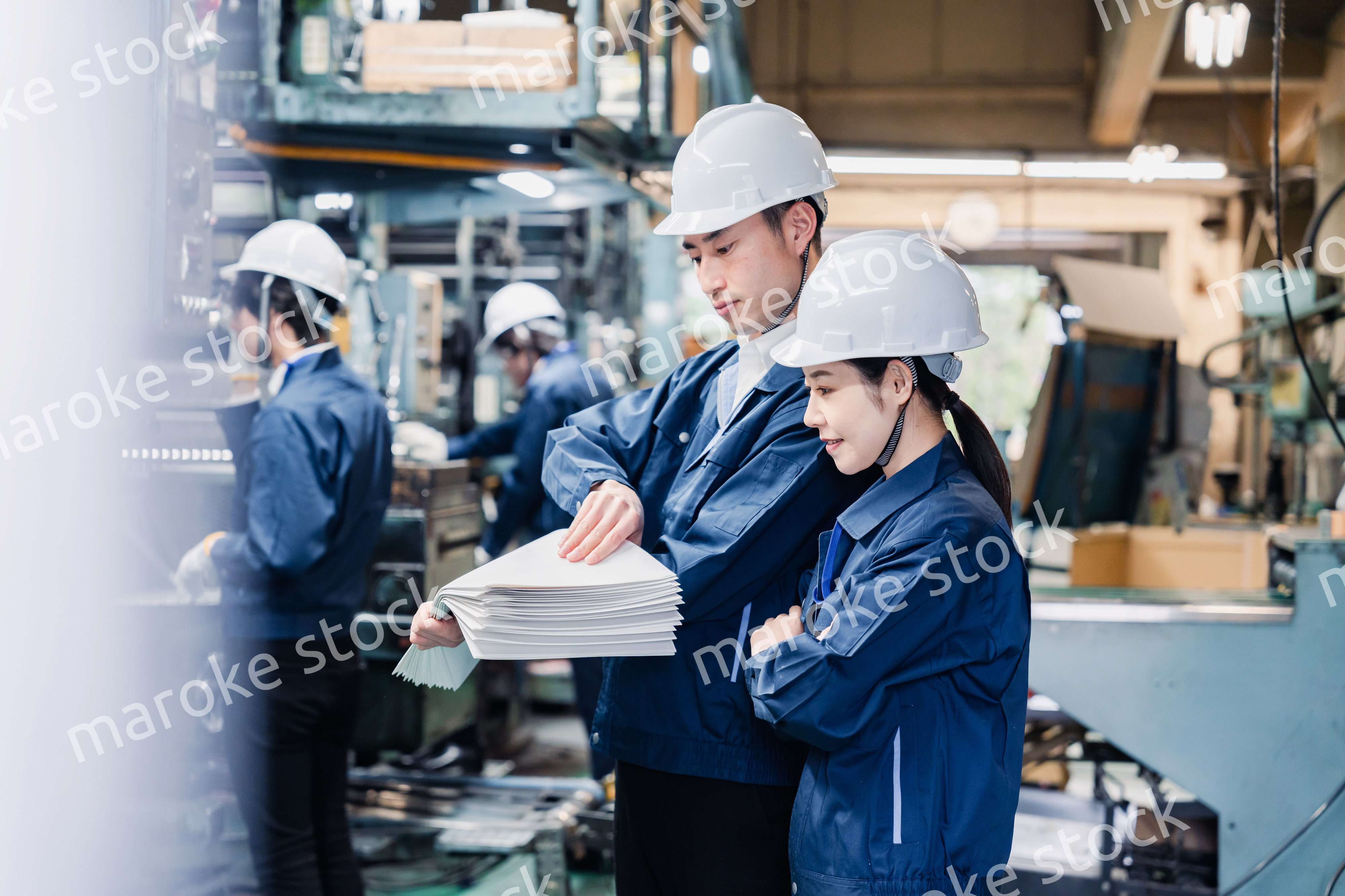 大量の紙資料を確認する工場スタッフ