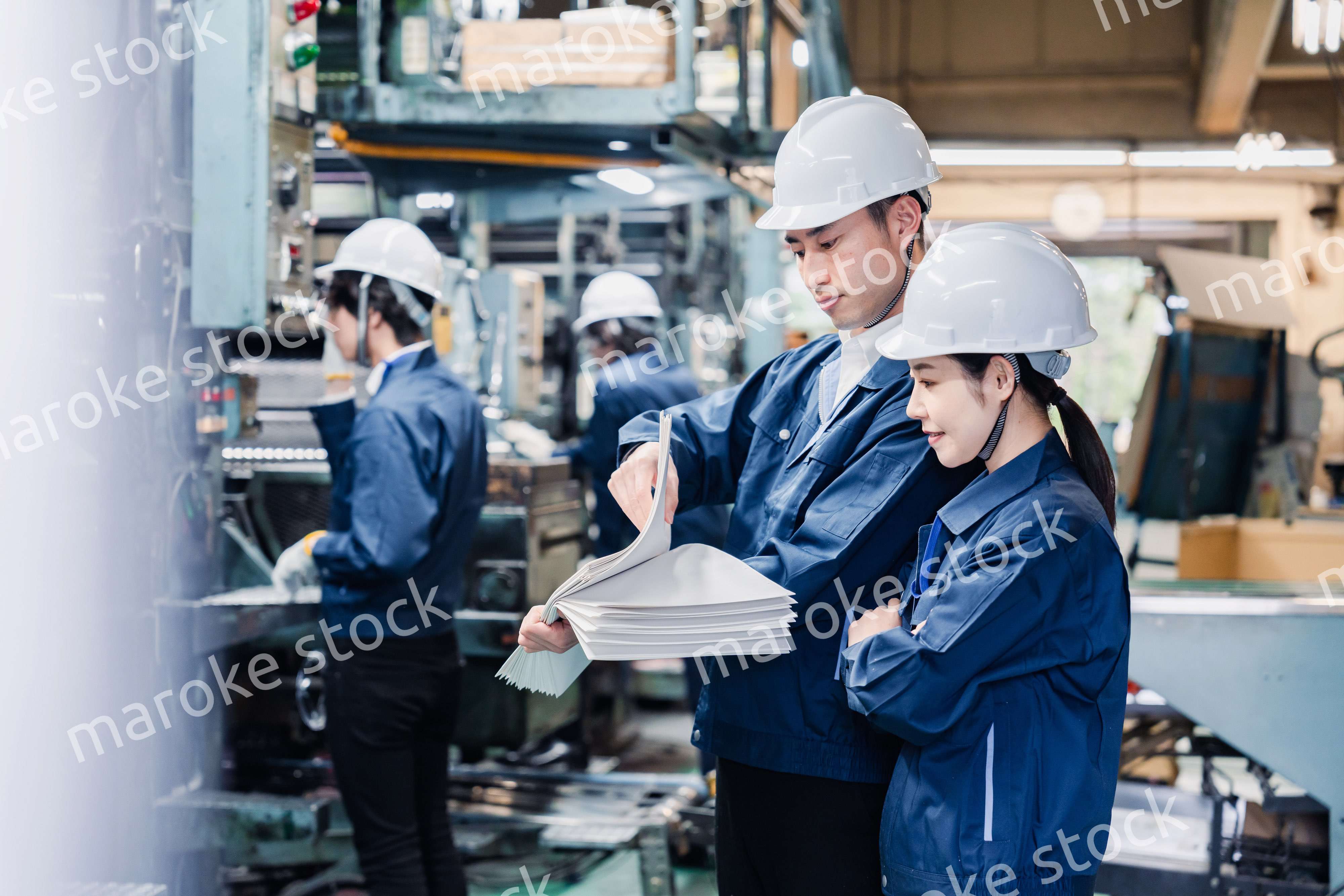 大量の紙資料を確認する工場スタッフ