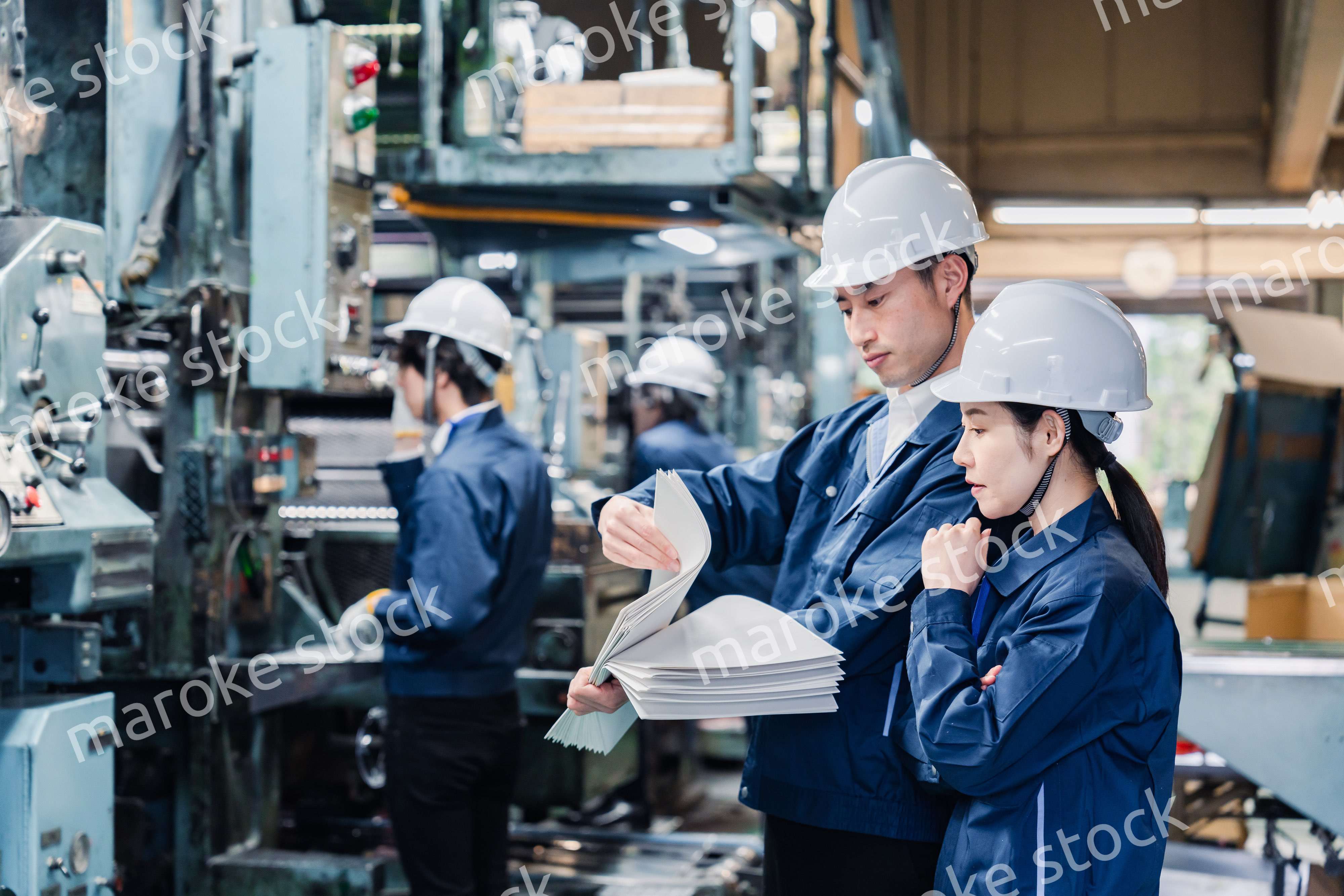 大量の紙資料を確認する工場スタッフ