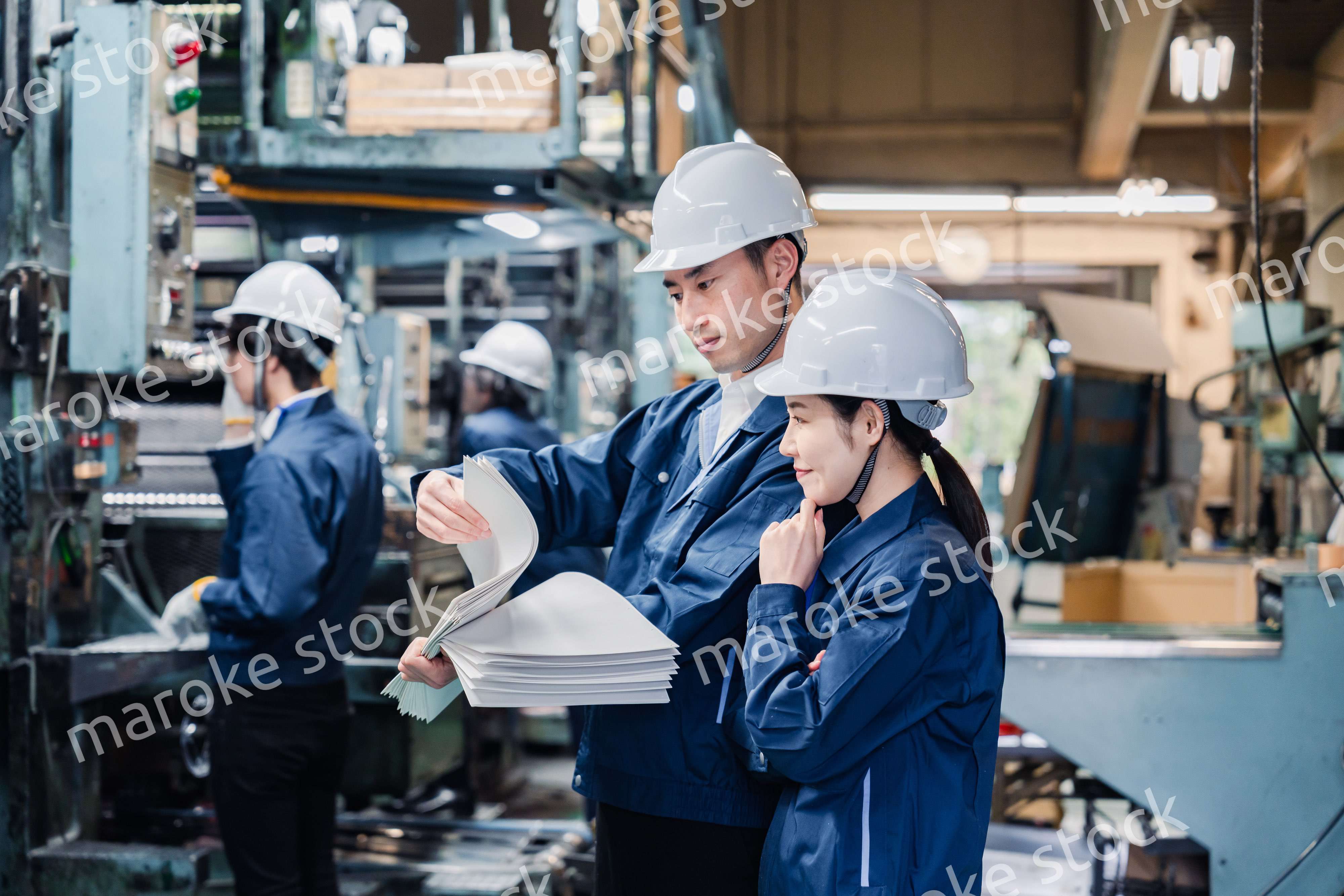 大量の紙資料を確認する工場スタッフ