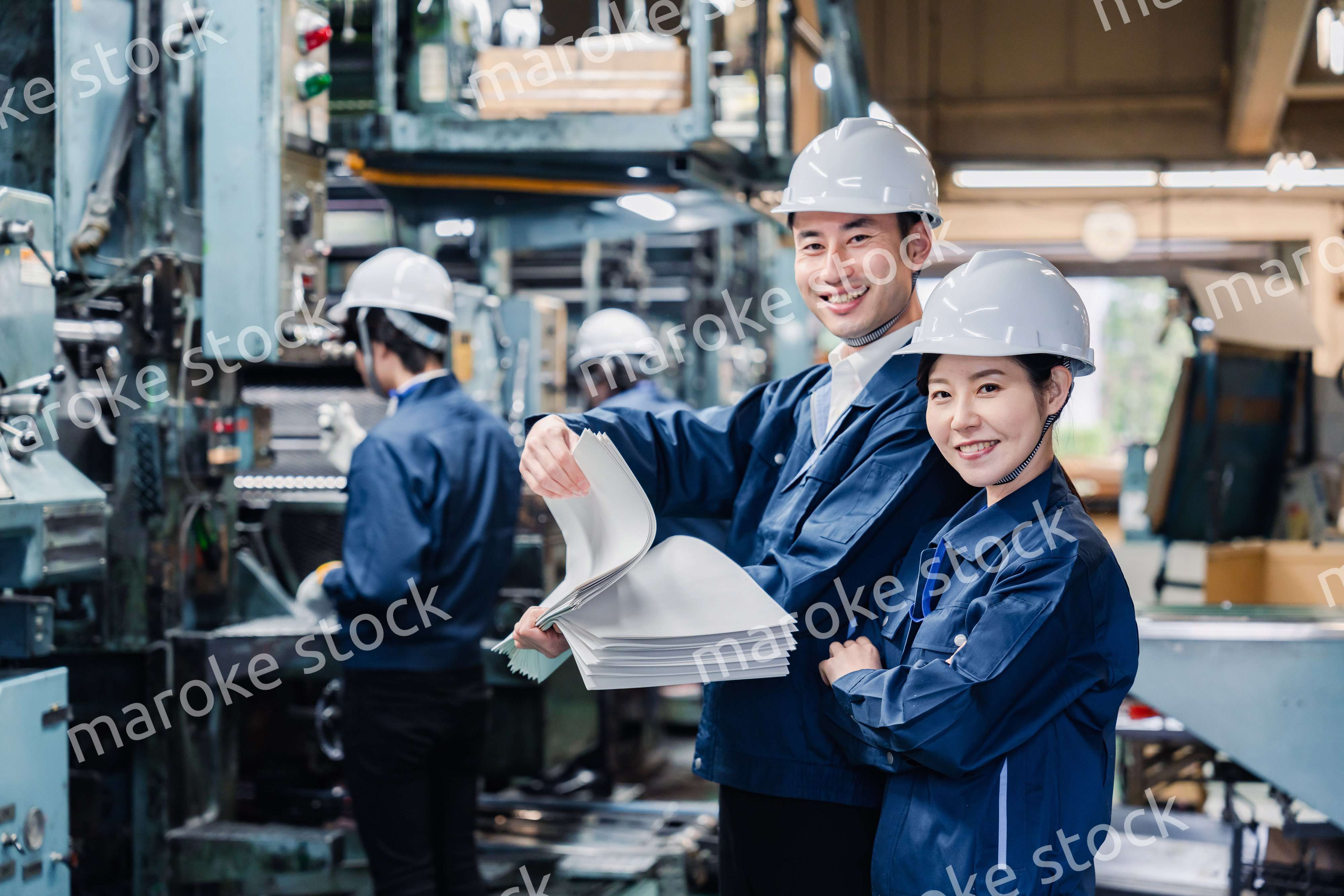 大量の紙資料を確認する工場スタッフ
