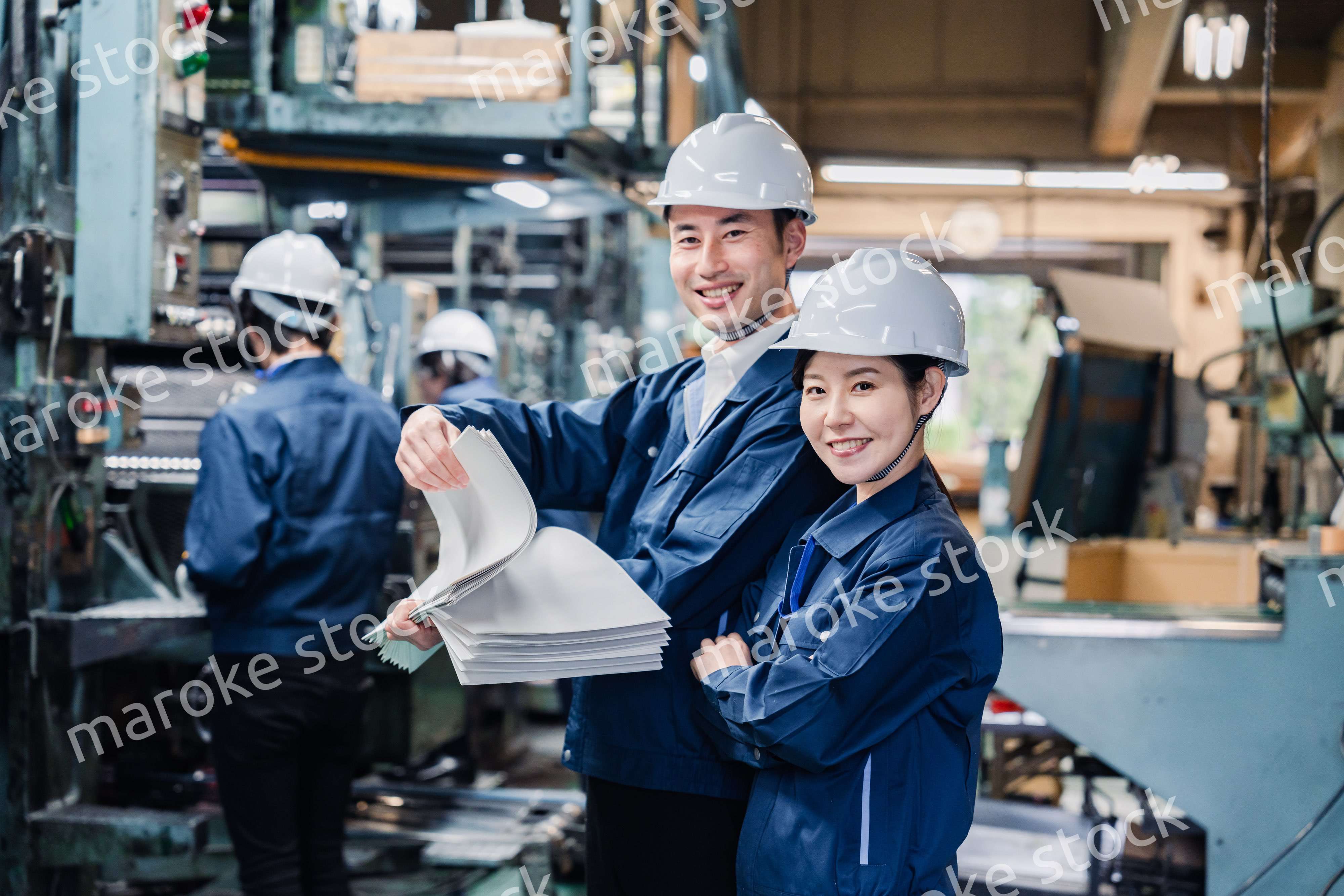 大量の紙資料を確認する工場スタッフ