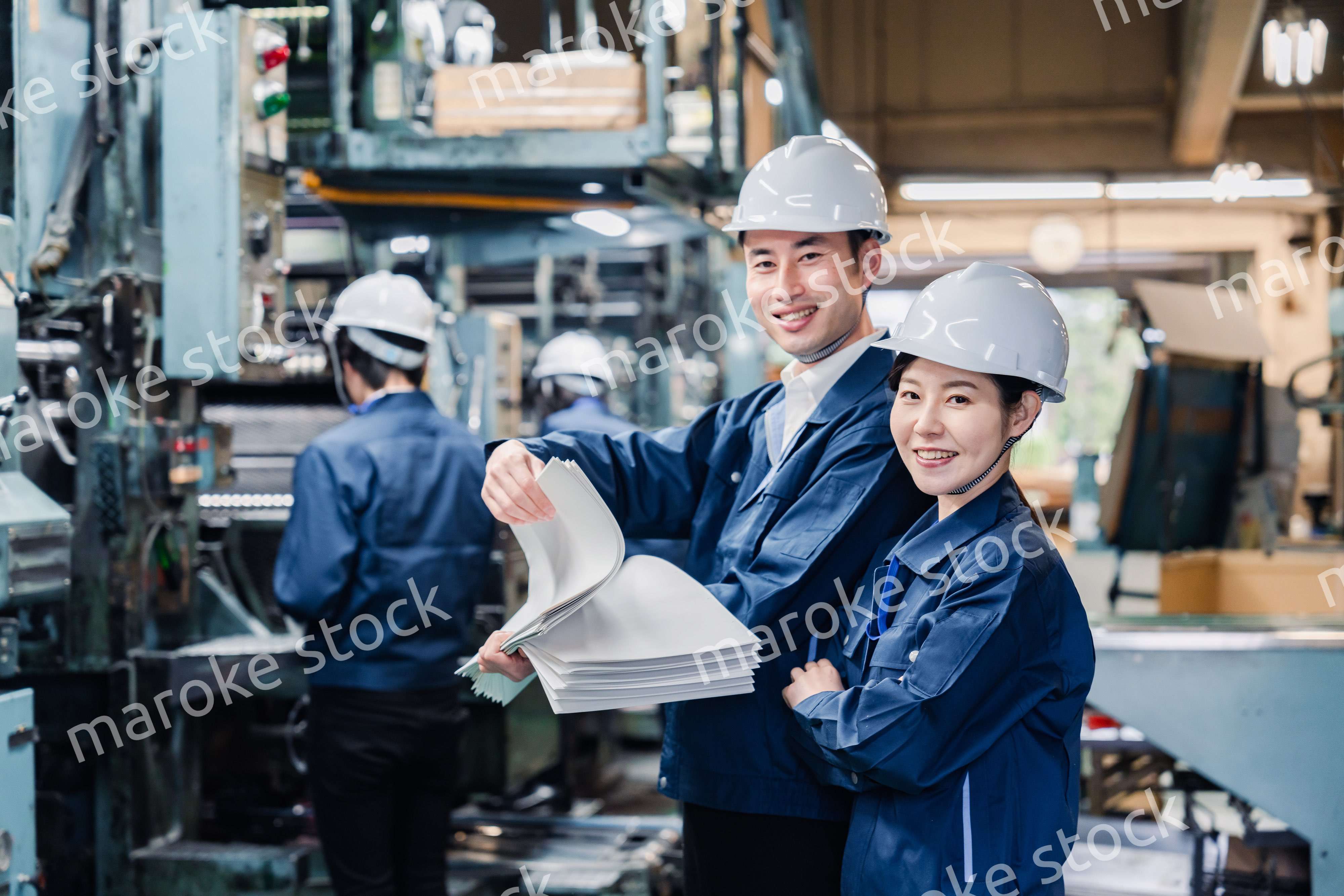 大量の紙資料を確認する工場スタッフ