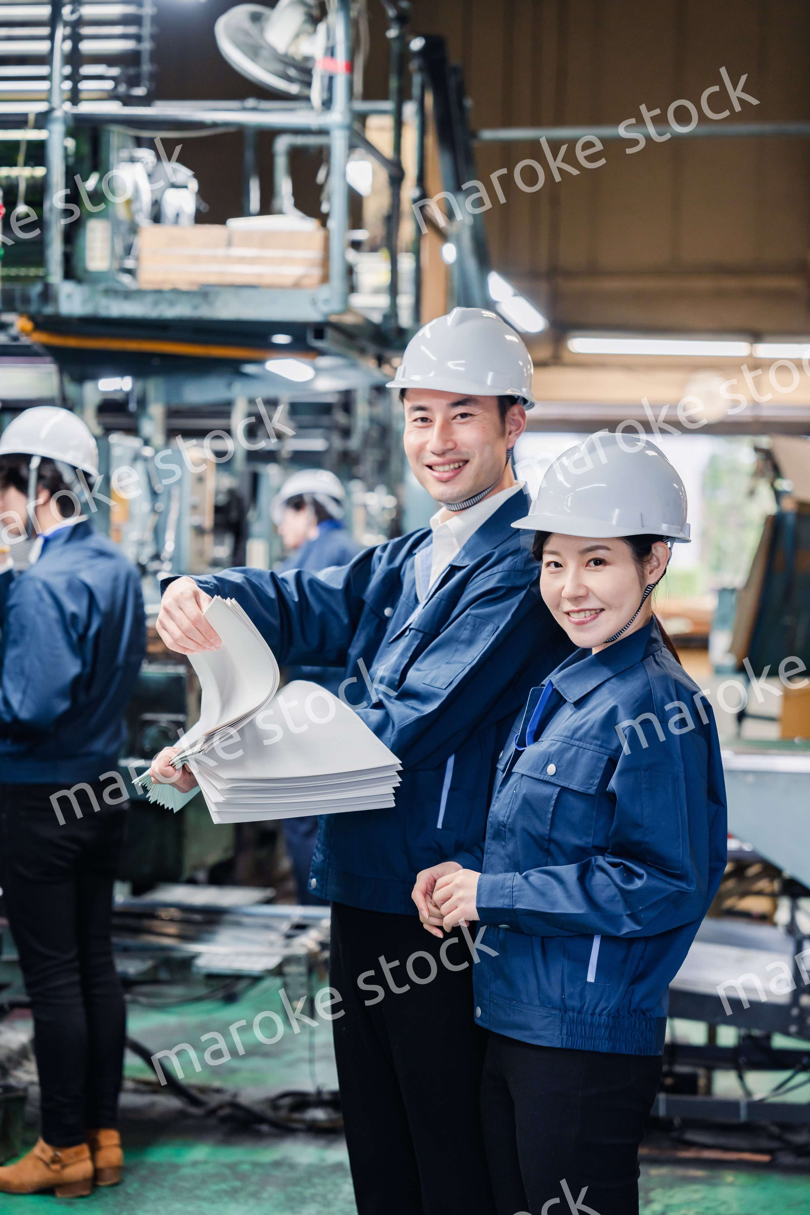 大量の紙資料を確認する工場スタッフ