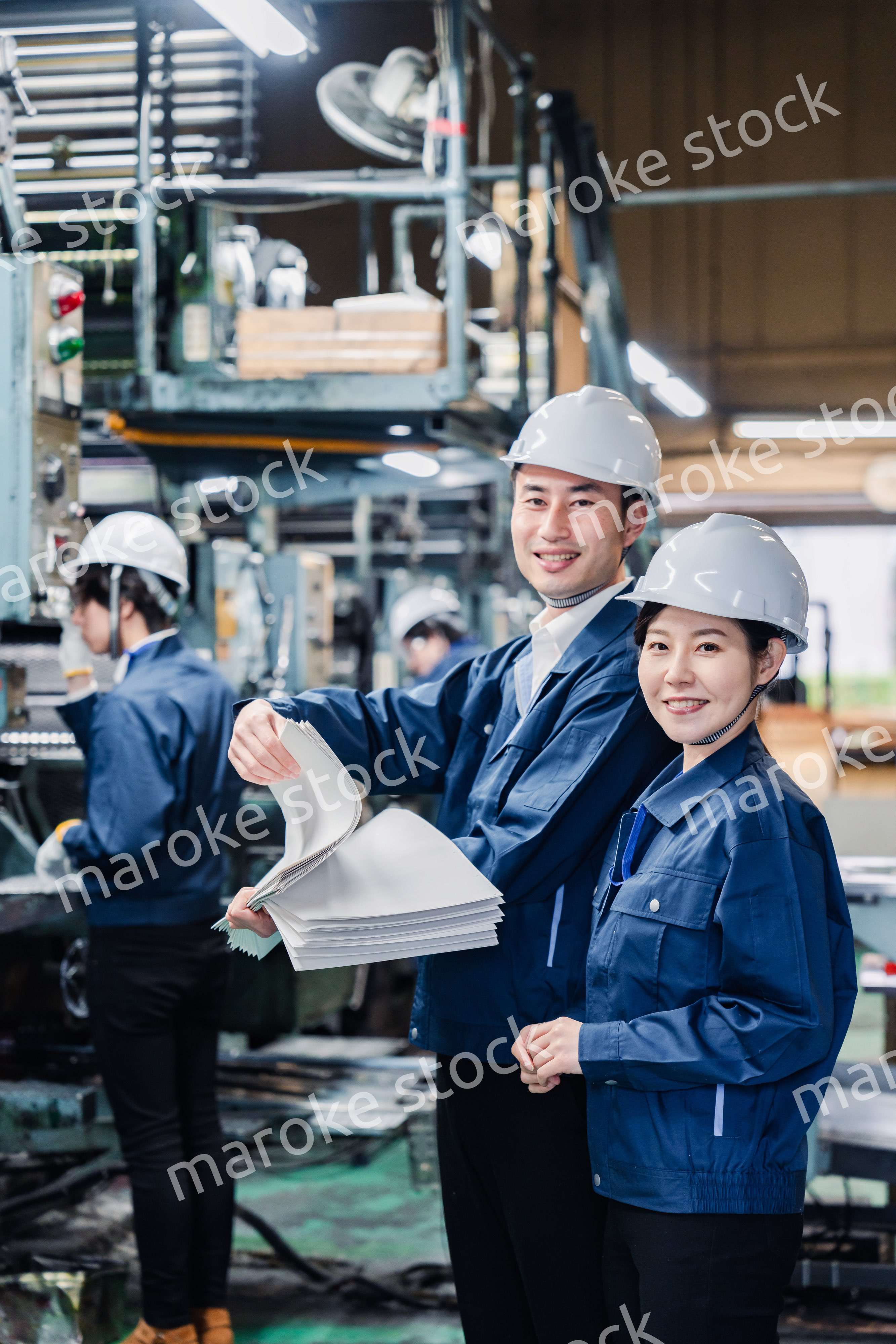 大量の紙資料を確認する工場スタッフ