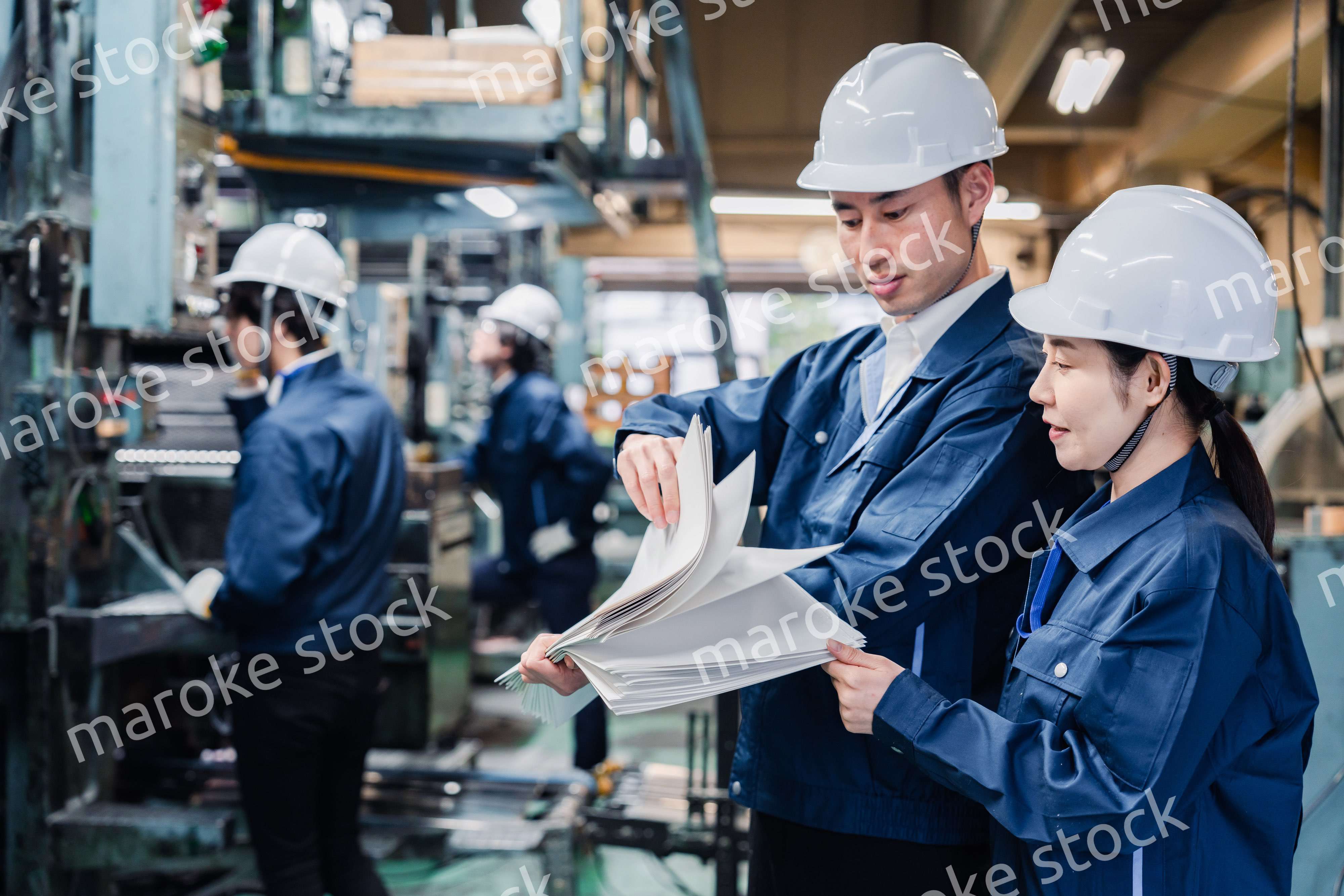 大量の紙資料を確認する工場スタッフ