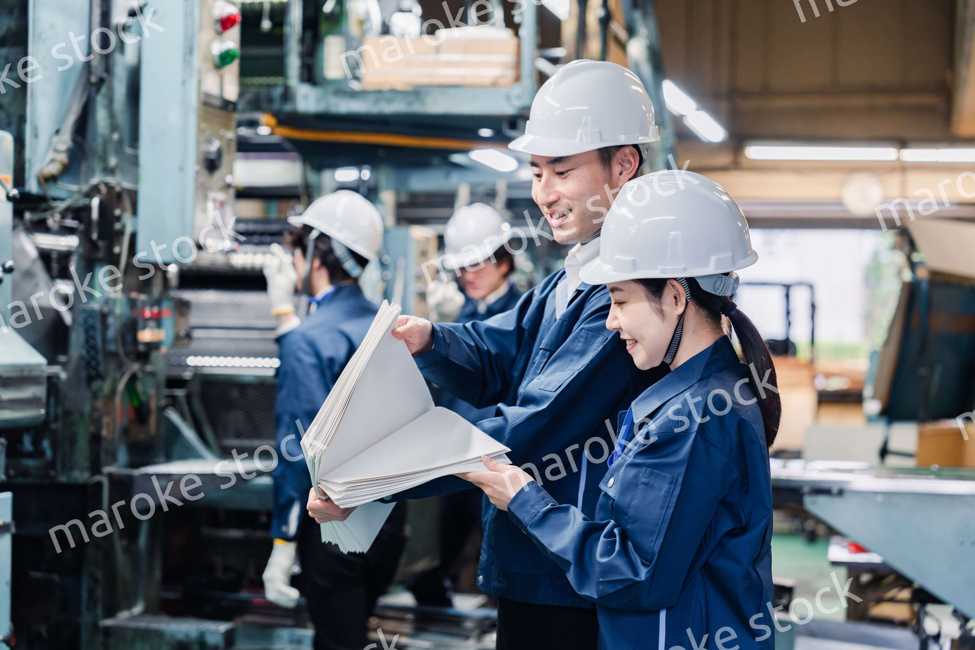 大量の紙資料を確認する工場スタッフ