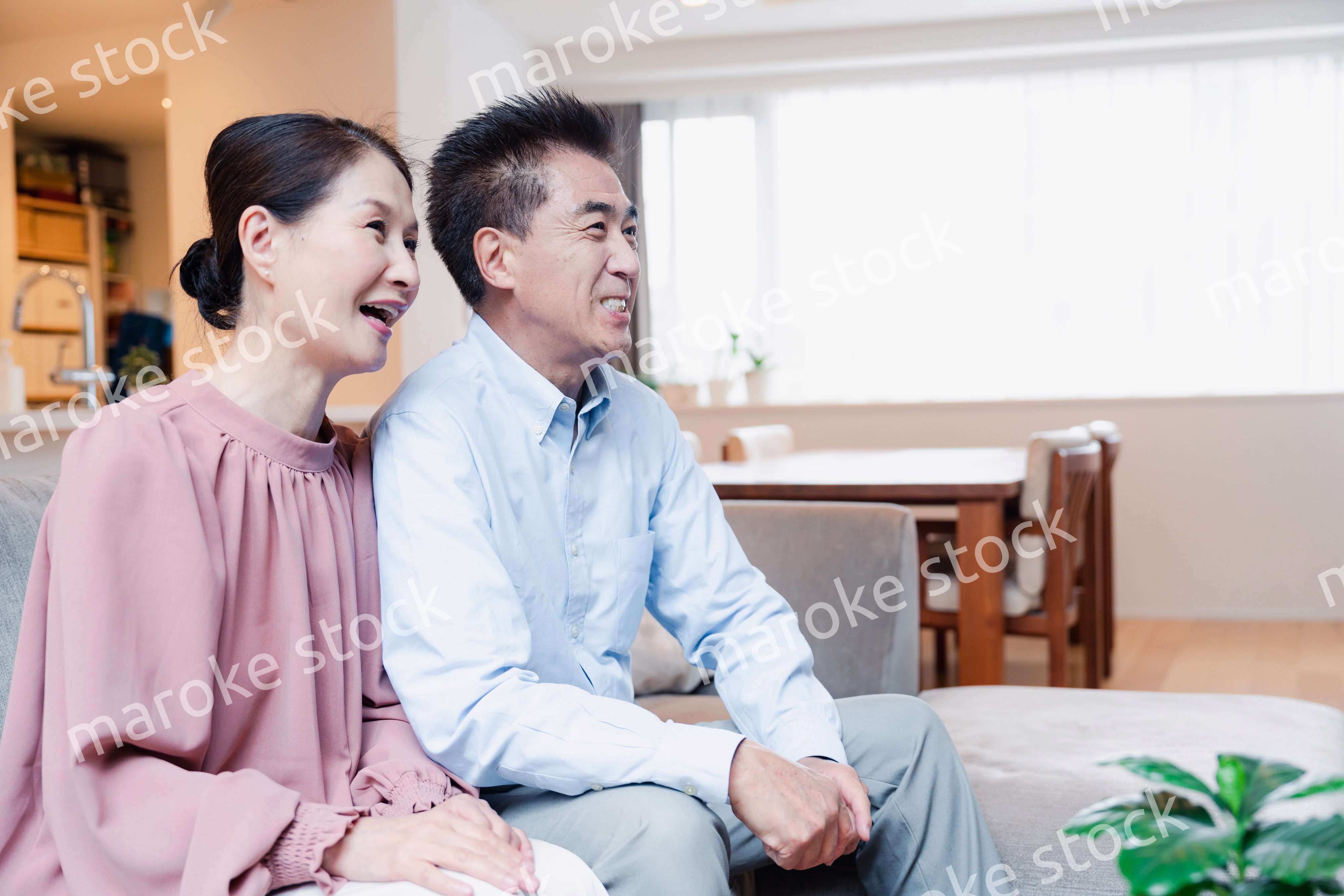 家でテレビを見るシニアの夫婦