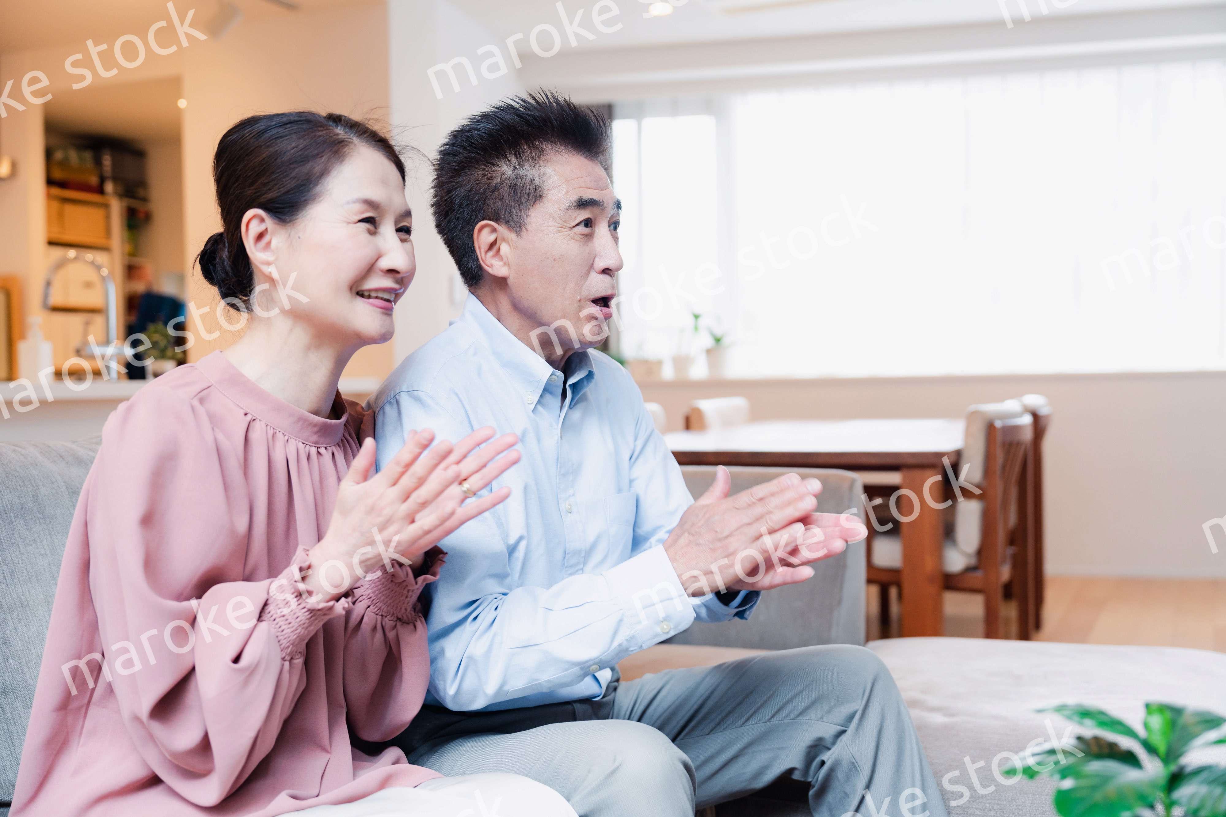 家でテレビを見るシニアの夫婦