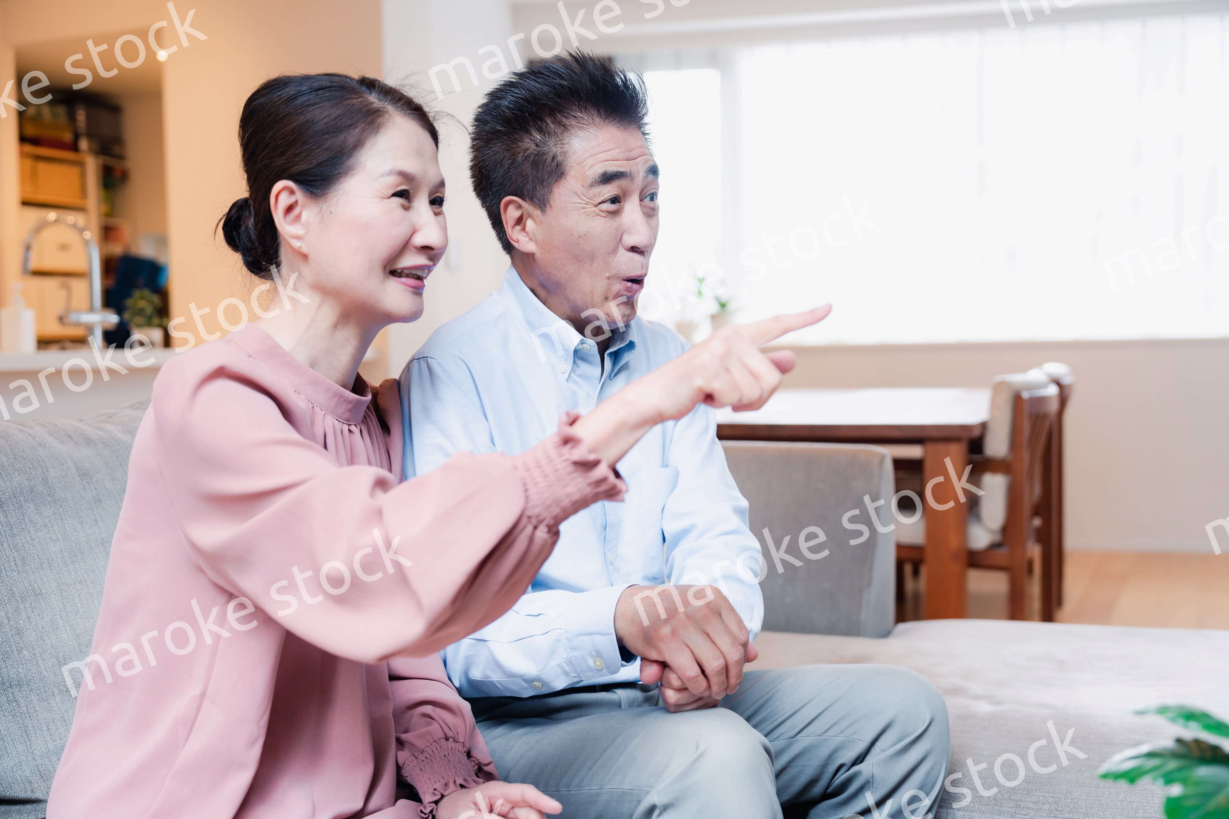 家でテレビを見るシニアの夫婦