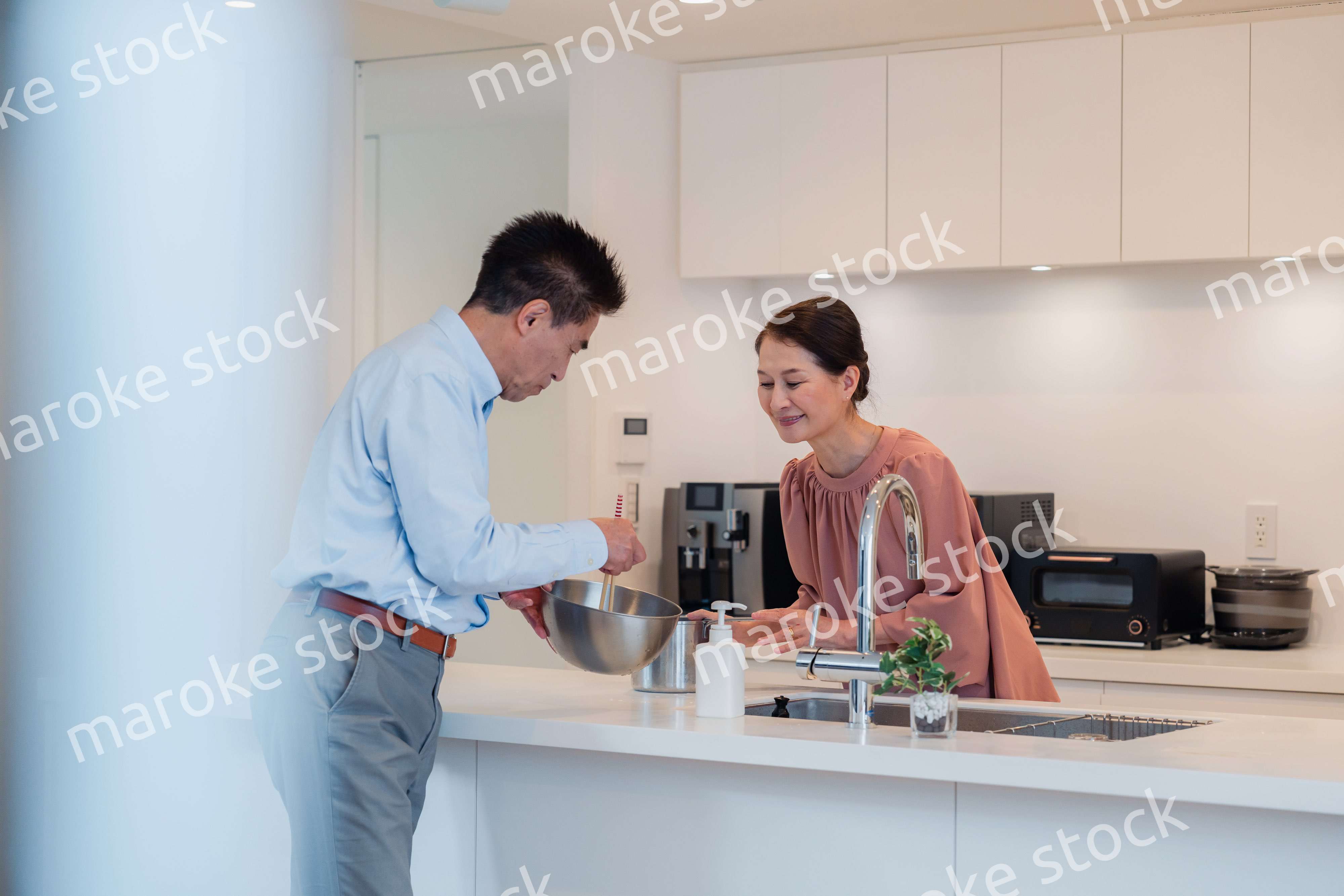 キッチンで一緒にクッキングを楽しむシニアの夫婦