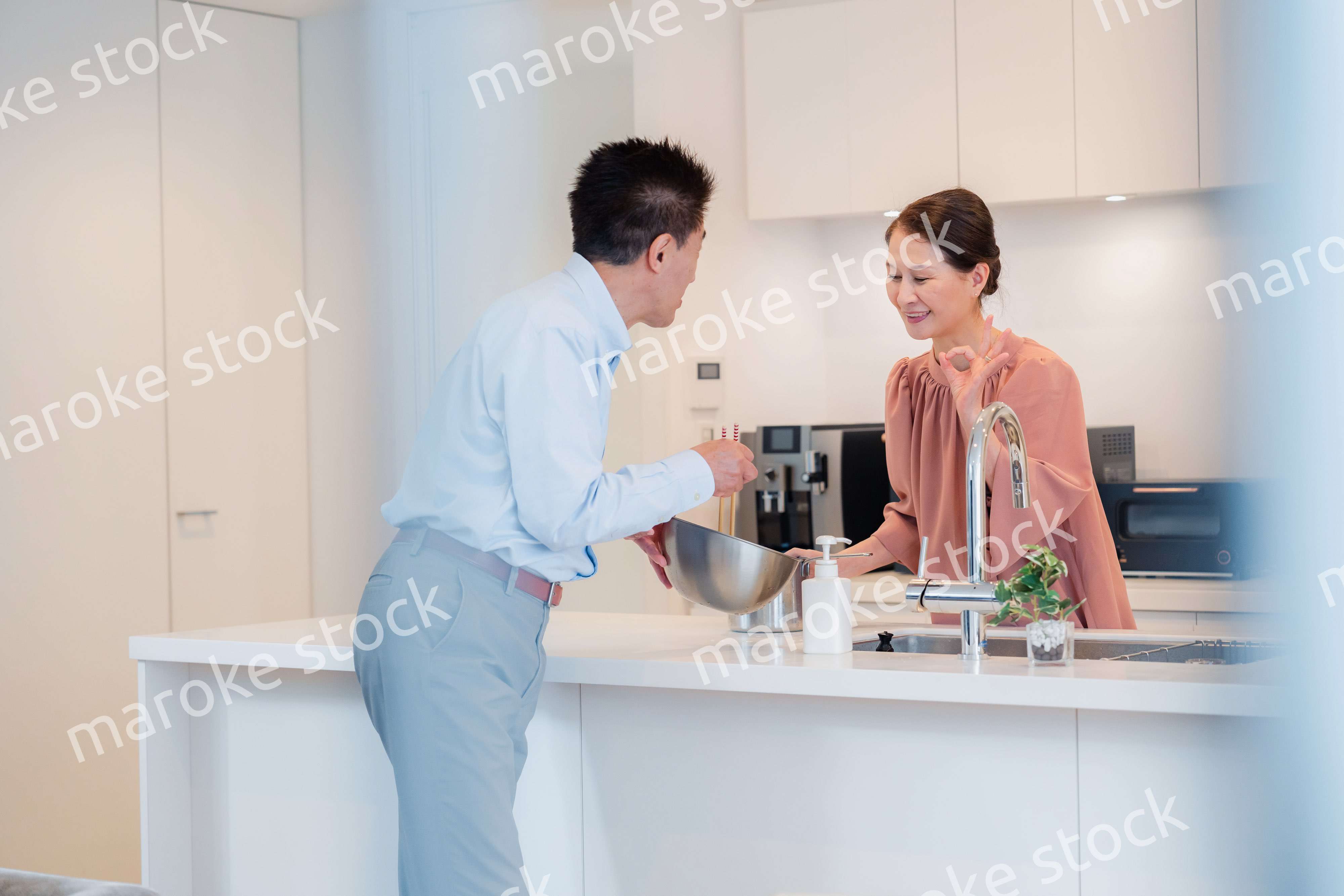 キッチンで一緒にクッキングを楽しむシニアの夫婦