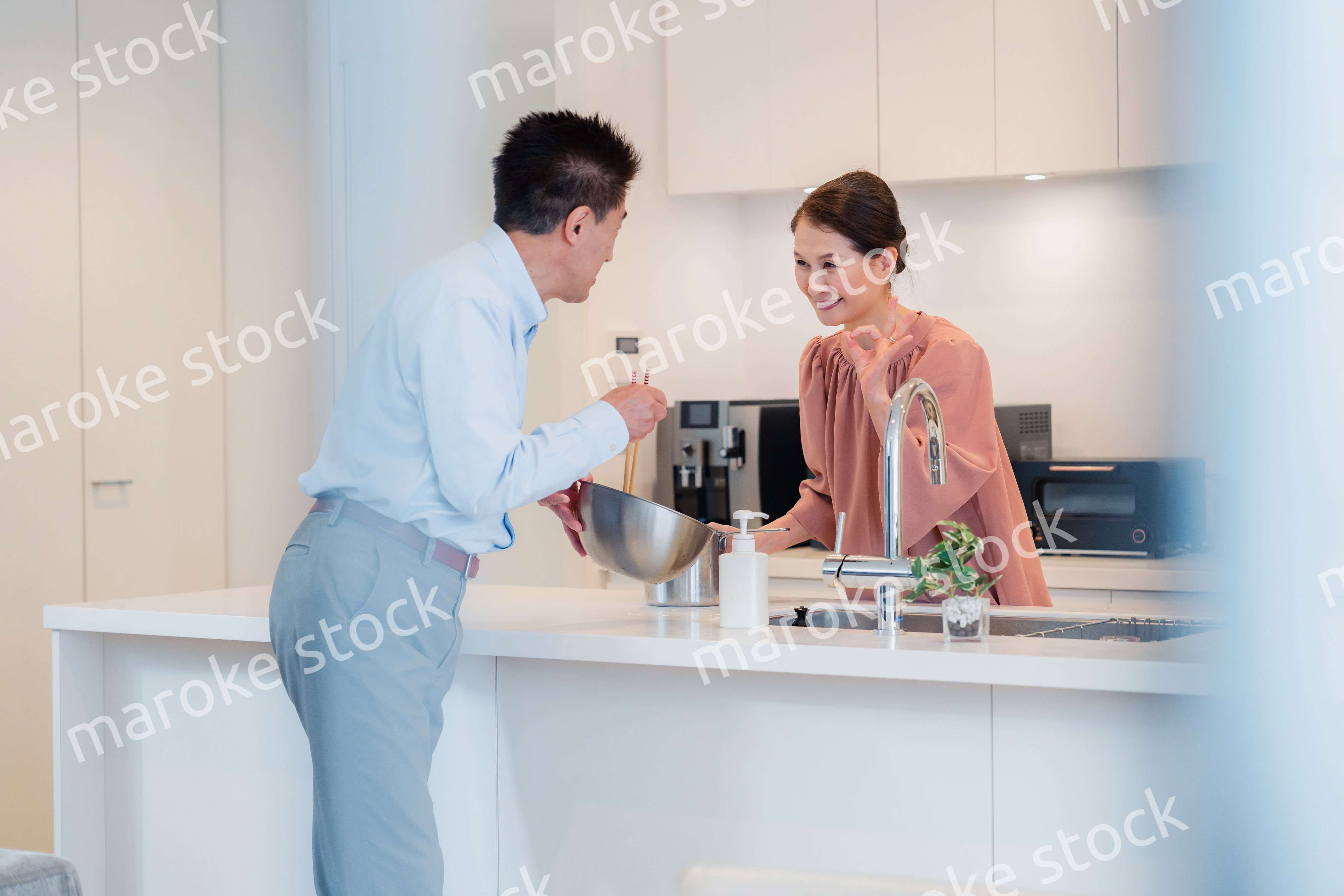 キッチンで一緒にクッキングを楽しむシニアの夫婦