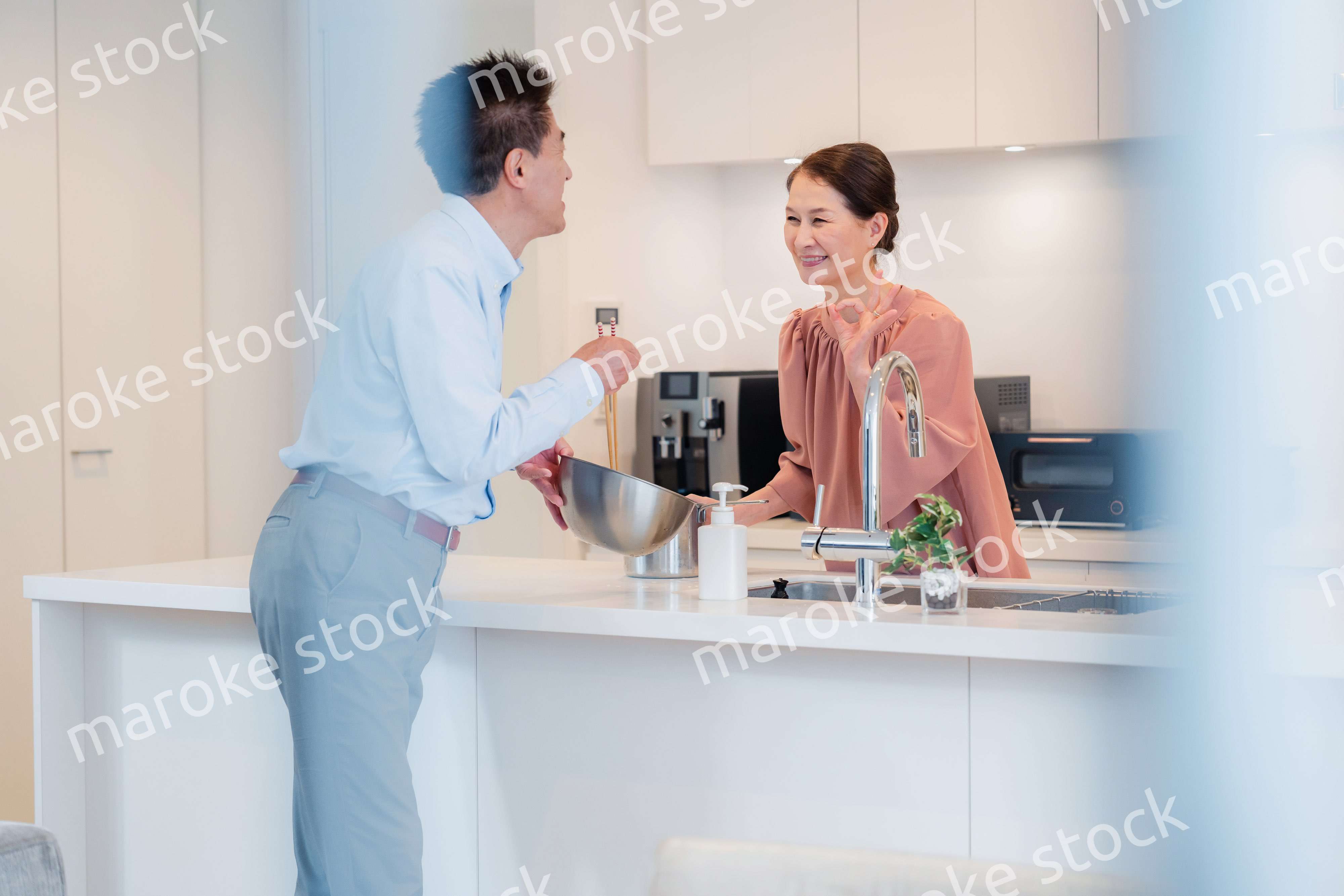 キッチンで一緒にクッキングを楽しむシニアの夫婦