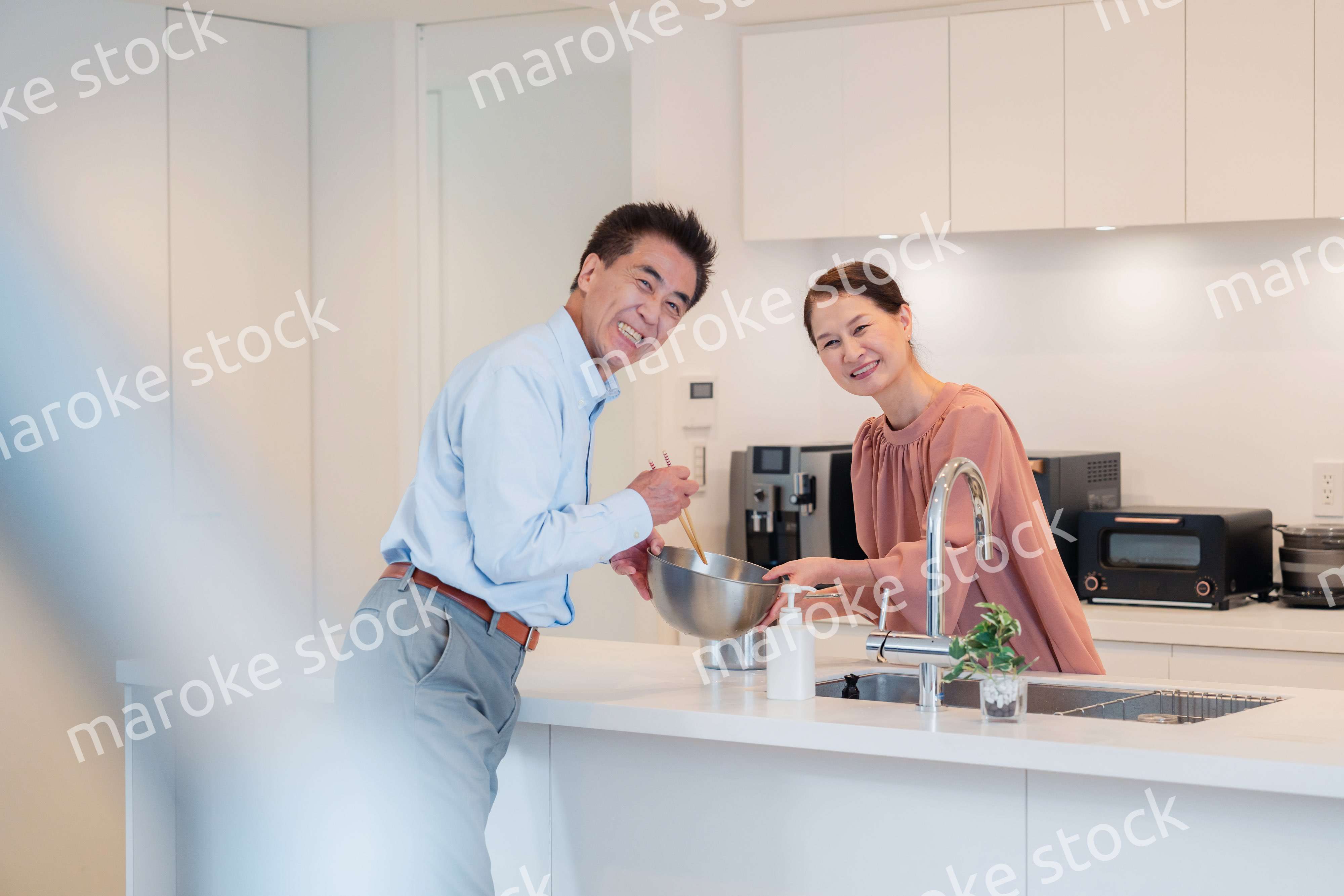 キッチンで一緒にクッキングを楽しむシニアの夫婦