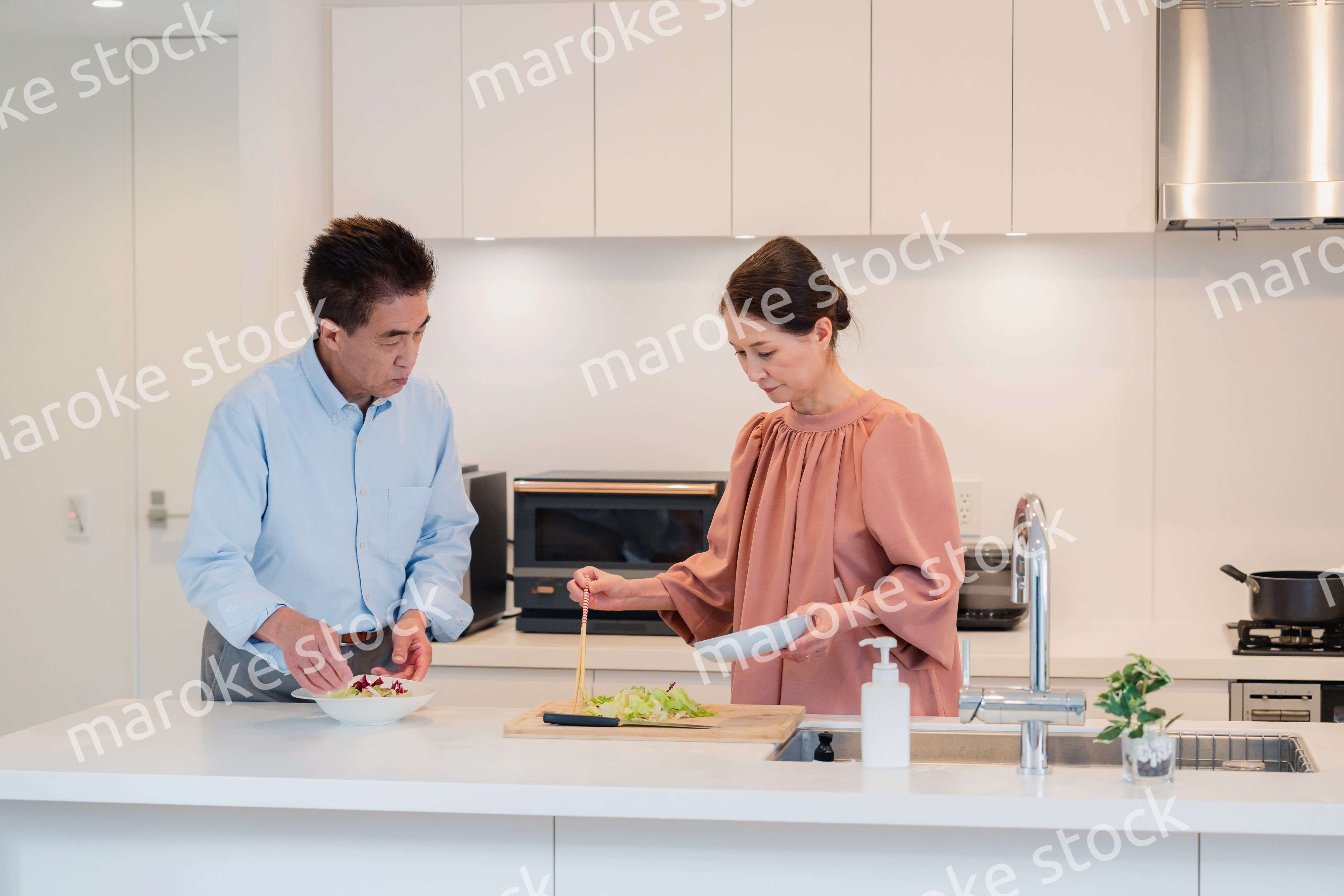 キッチンで一緒にクッキングを楽しむシニアの夫婦