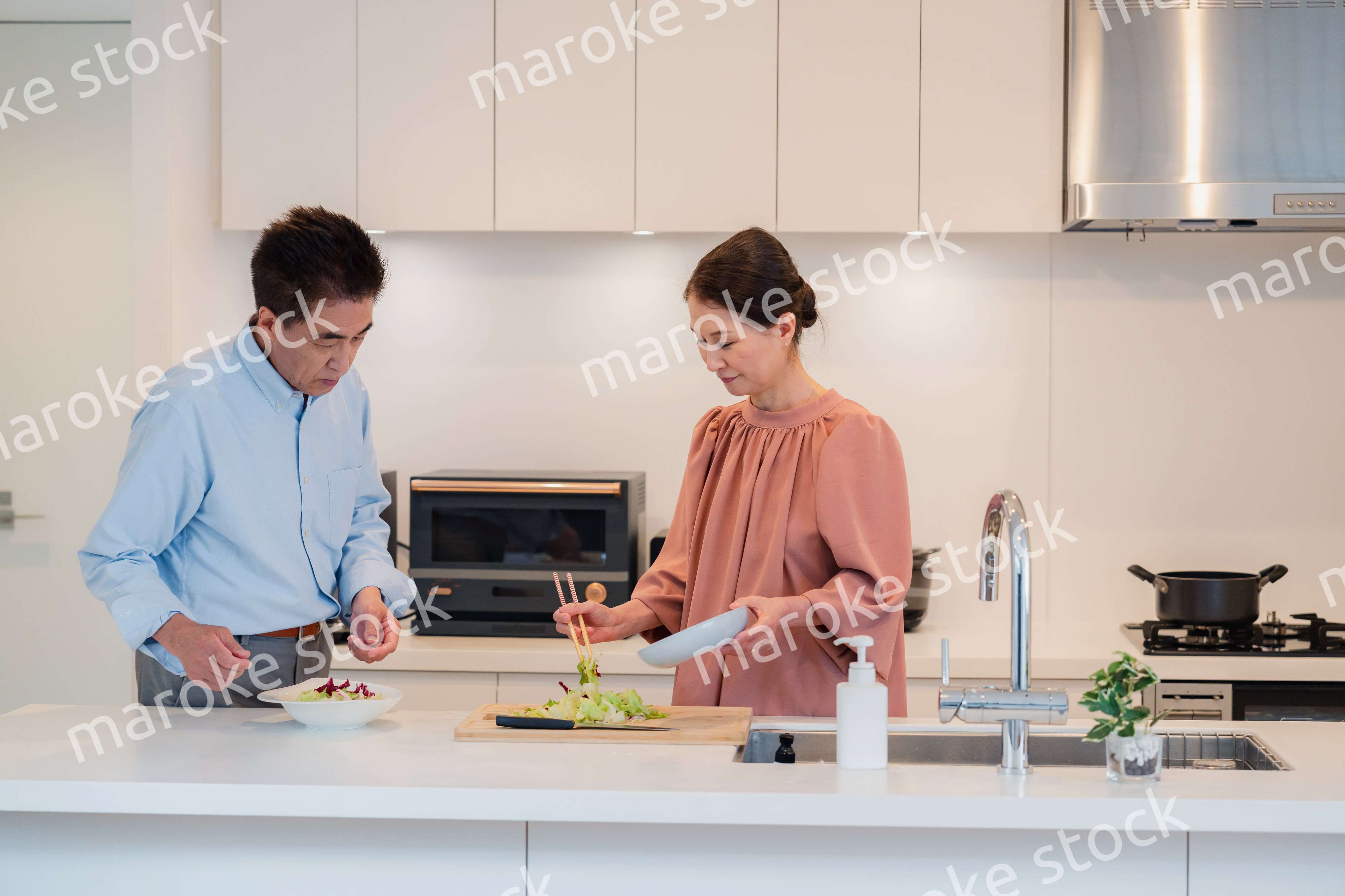 キッチンで一緒にクッキングを楽しむシニアの夫婦