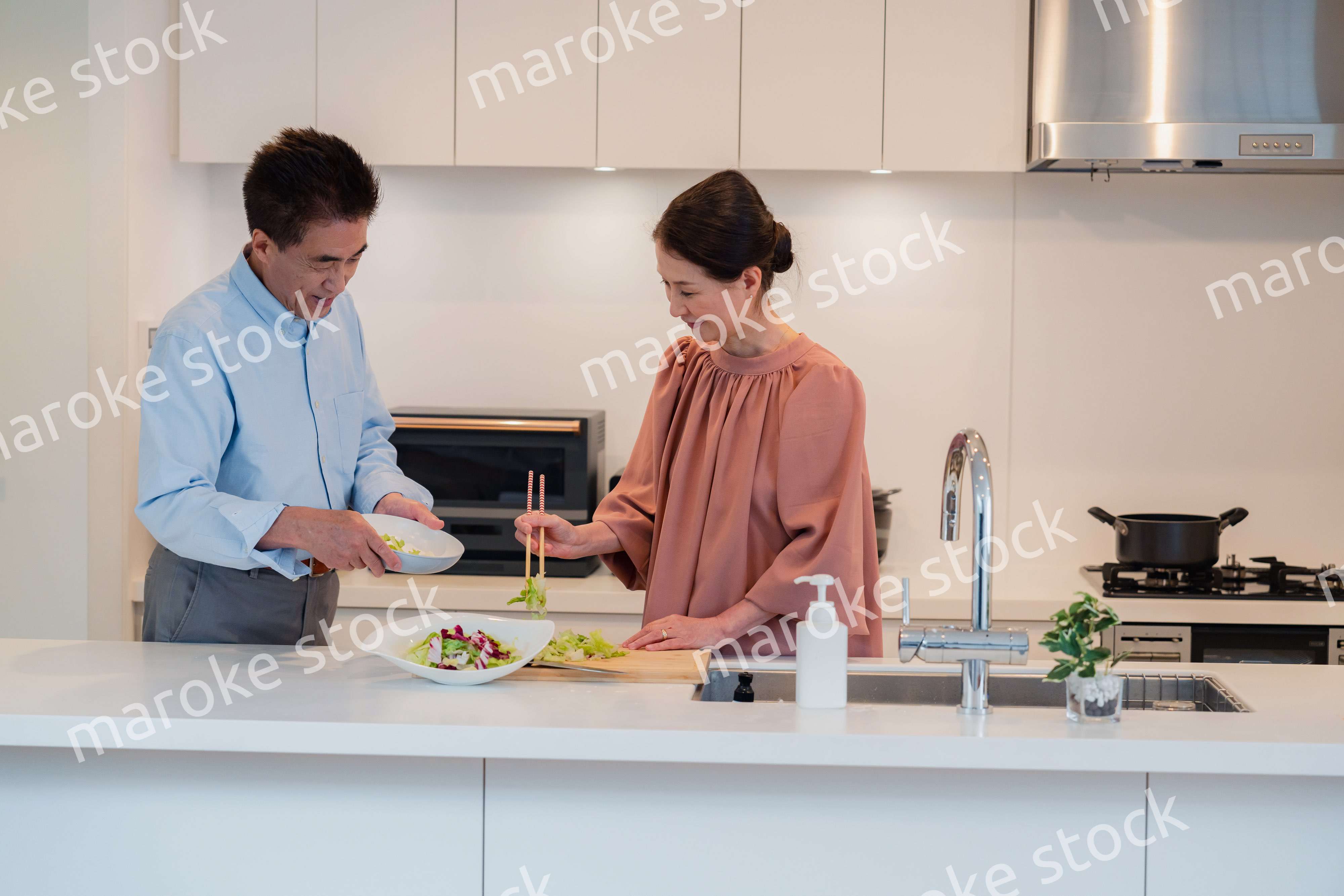 キッチンで一緒にクッキングを楽しむシニアの夫婦