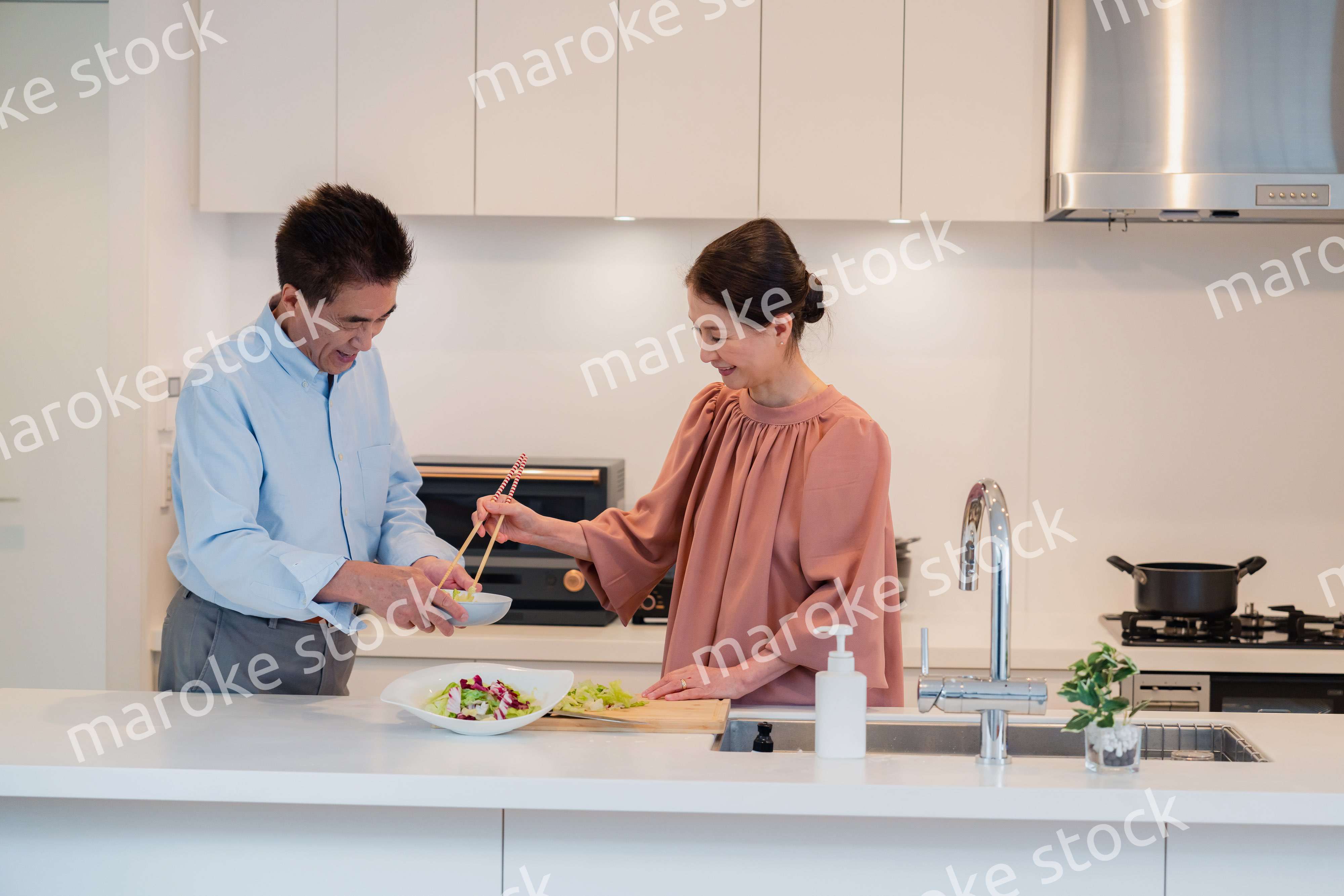 キッチンで一緒にクッキングを楽しむシニアの夫婦