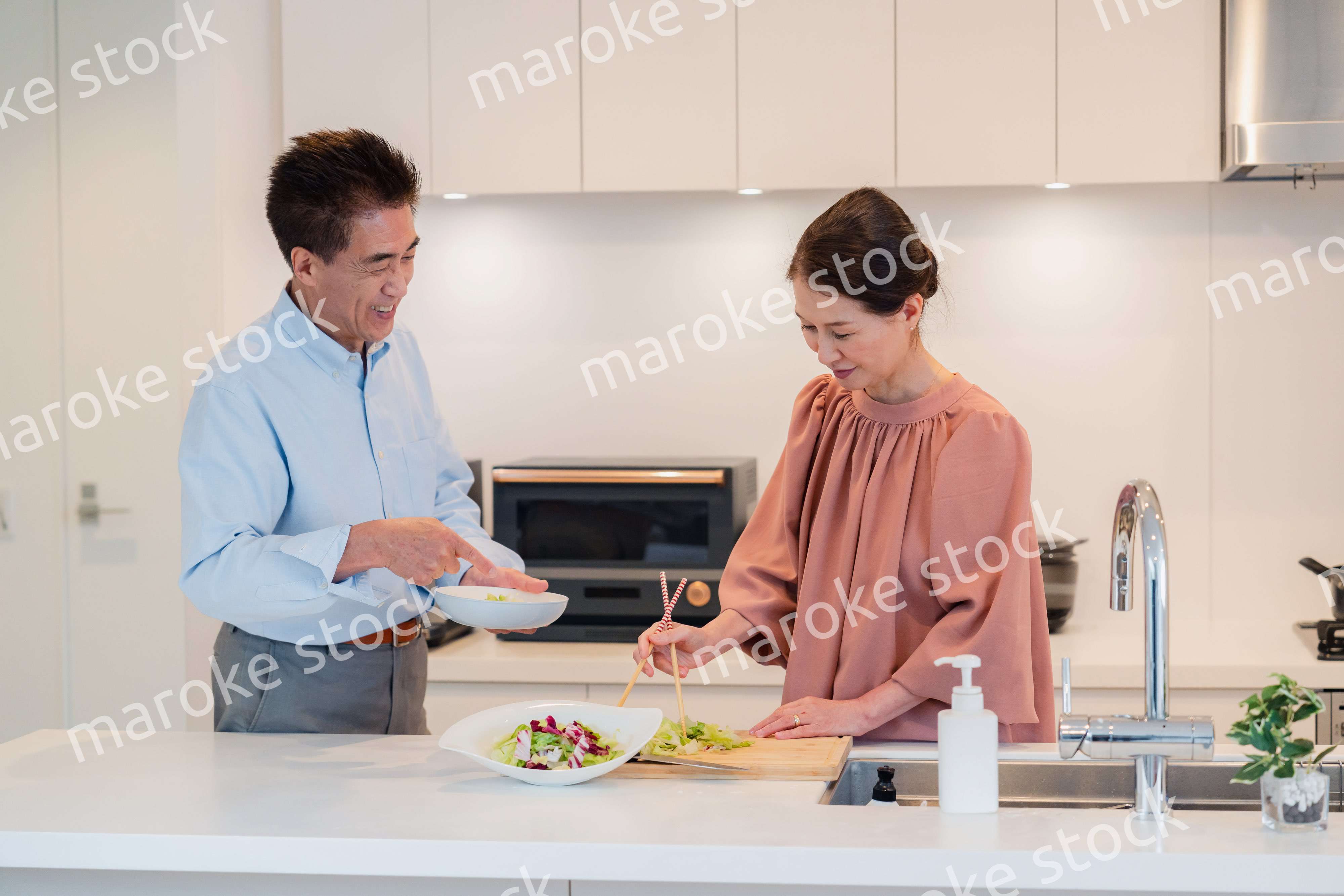 キッチンで一緒にクッキングを楽しむシニアの夫婦