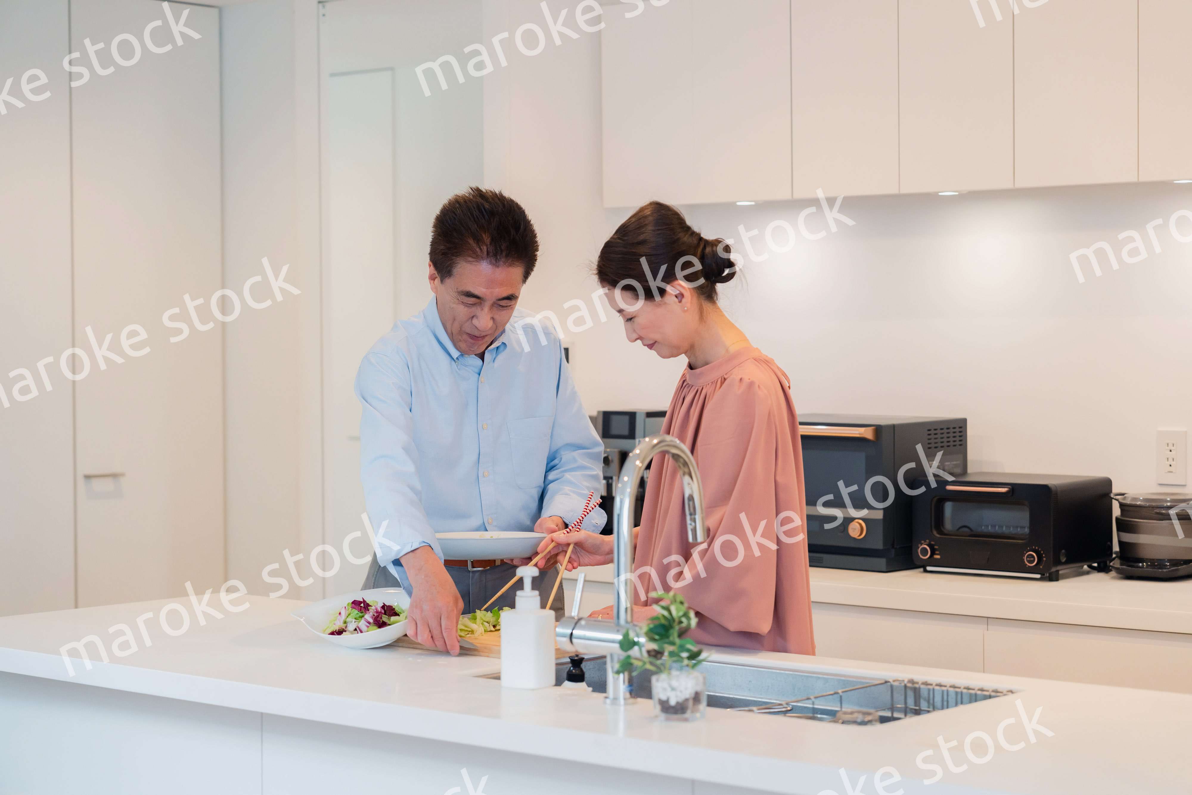 キッチンで一緒にクッキングを楽しむシニアの夫婦