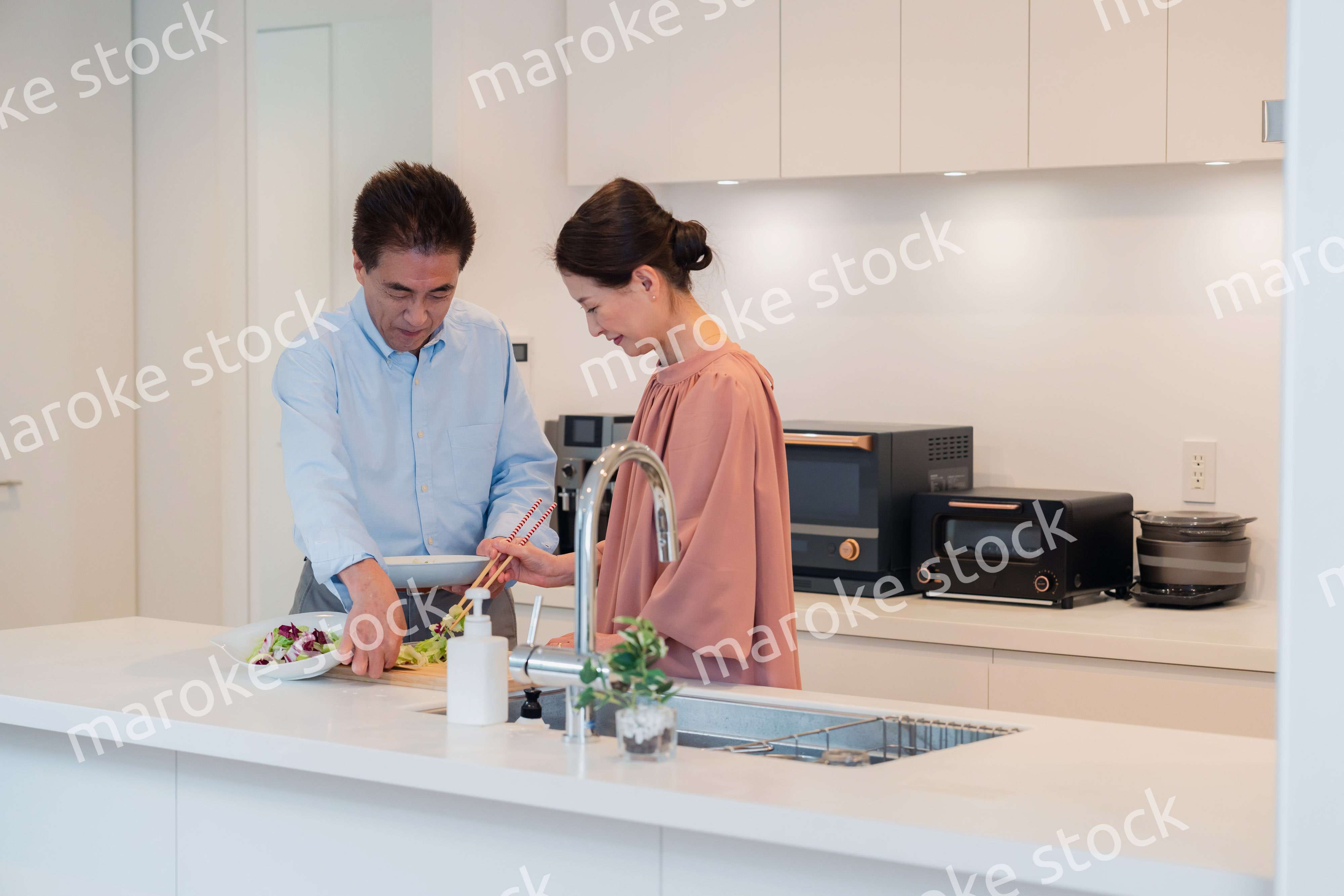 キッチンで一緒にクッキングを楽しむシニアの夫婦