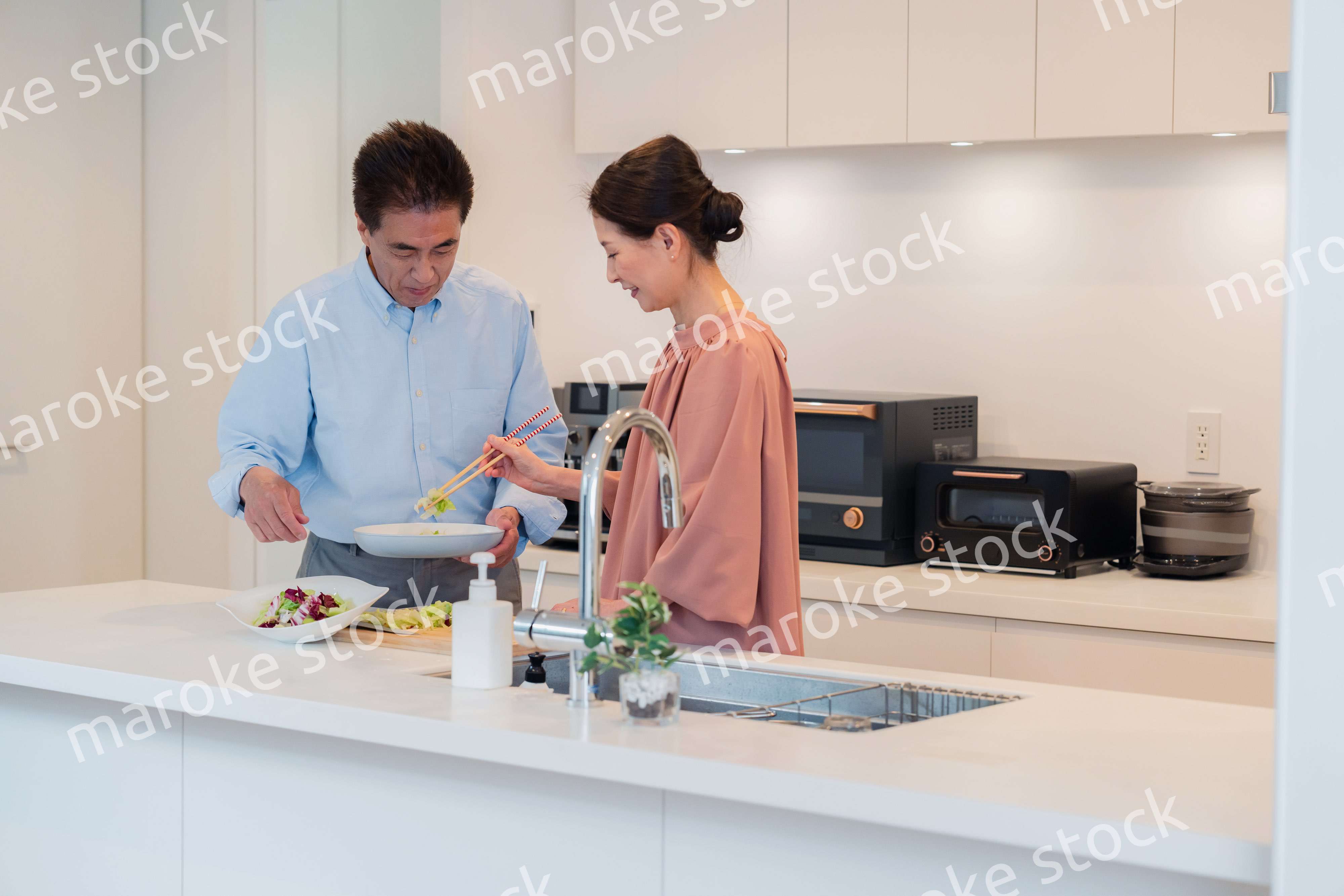 キッチンで一緒にクッキングを楽しむシニアの夫婦