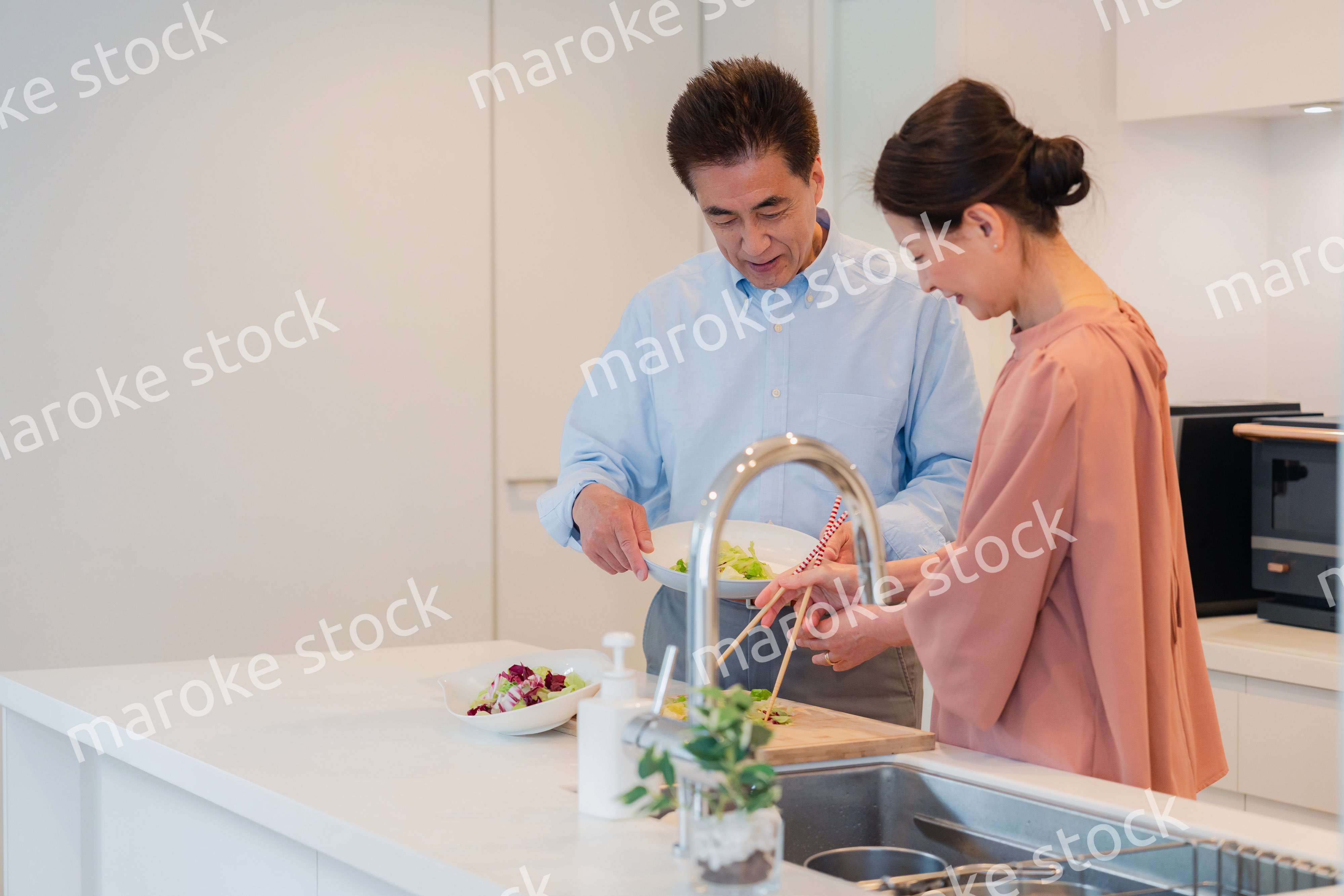 キッチンで一緒にクッキングを楽しむシニアの夫婦