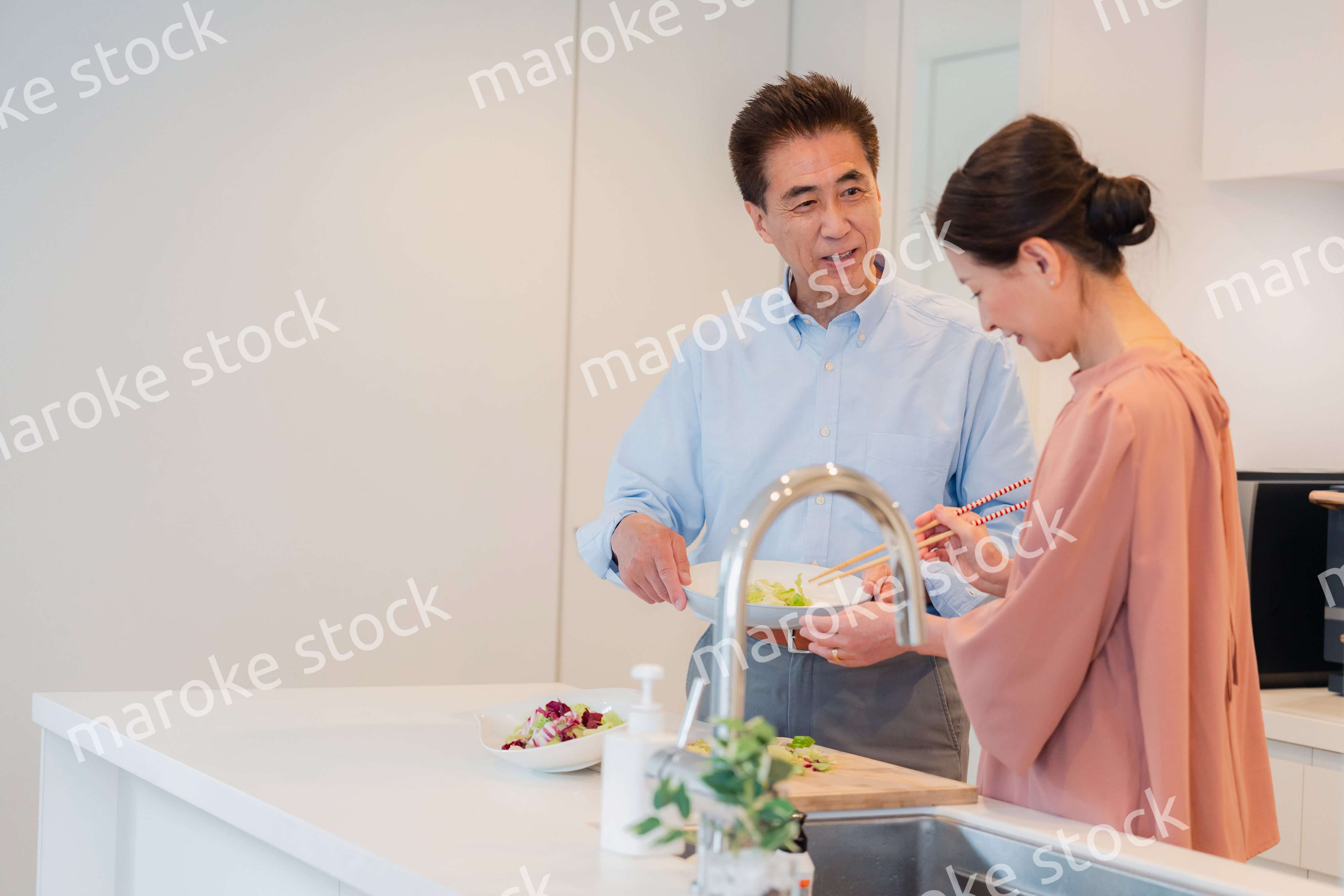 キッチンで一緒にクッキングを楽しむシニアの夫婦