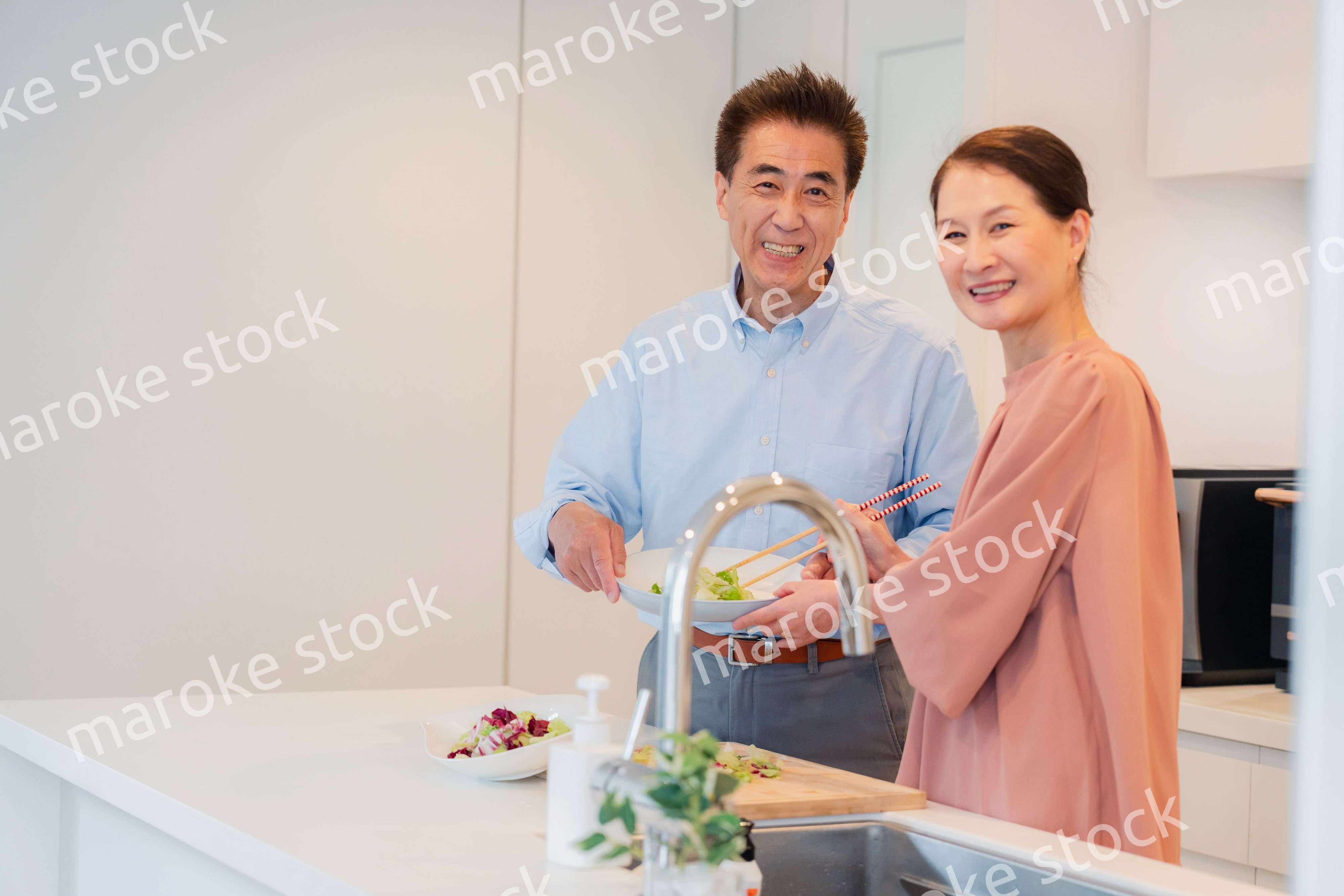 キッチンで一緒にクッキングを楽しむシニアの夫婦