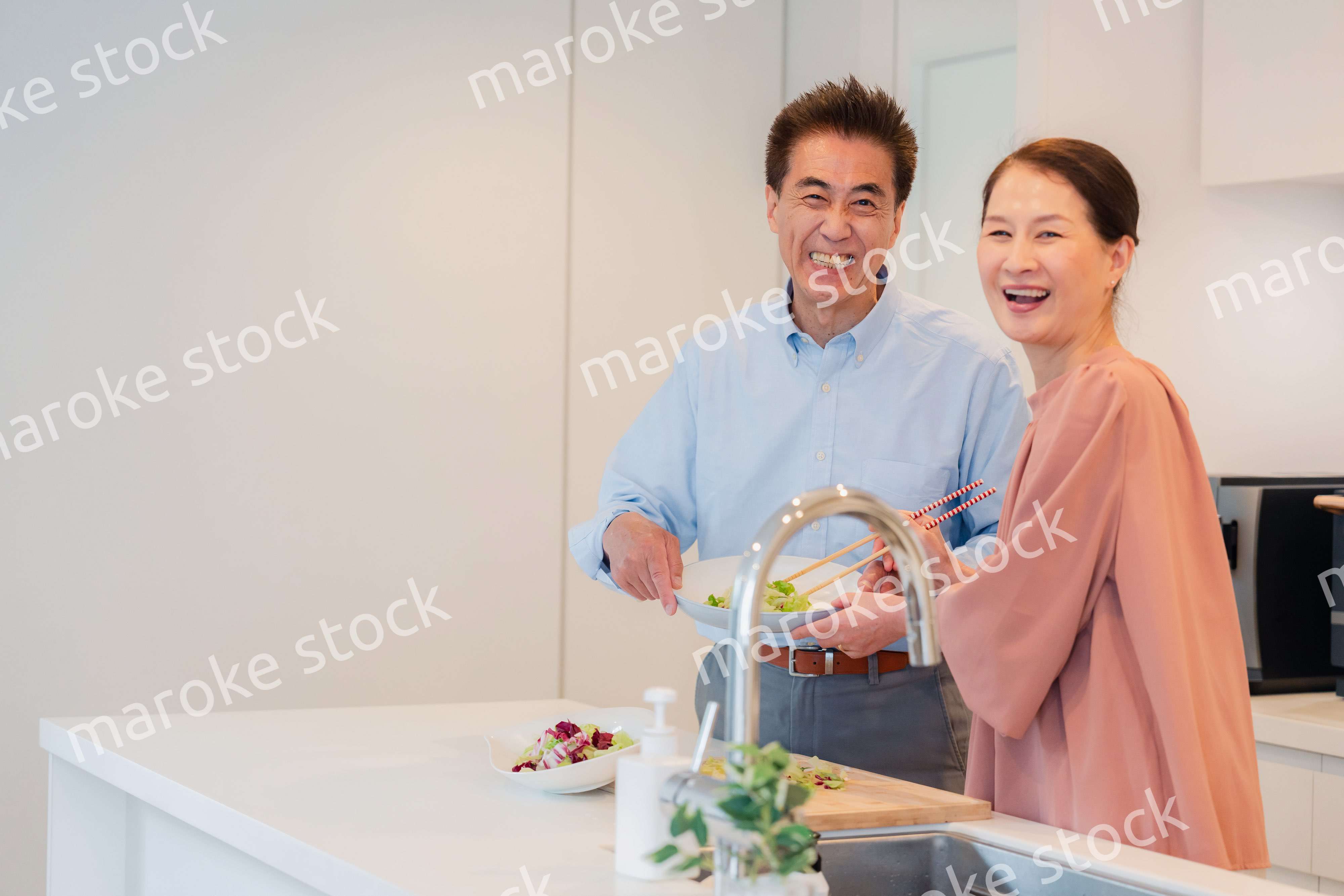 キッチンで一緒にクッキングを楽しむシニアの夫婦