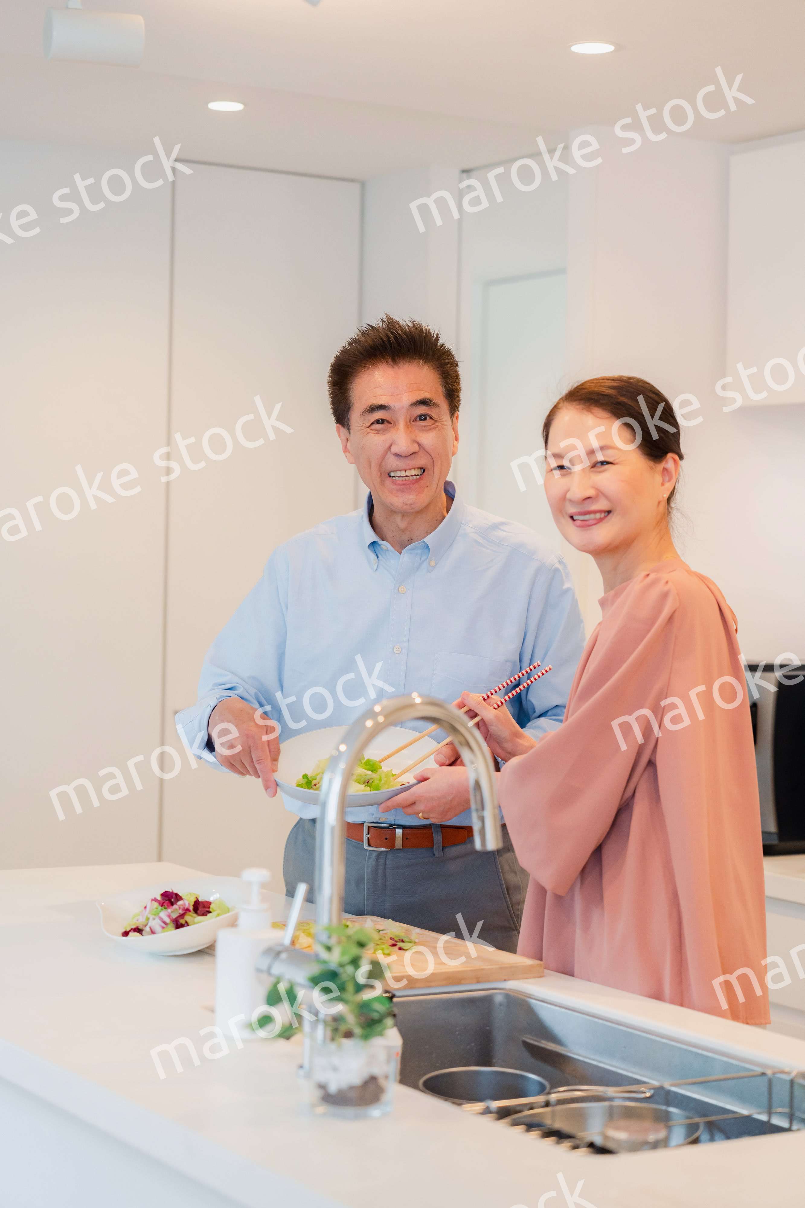 キッチンで一緒にクッキングを楽しむシニアの夫婦