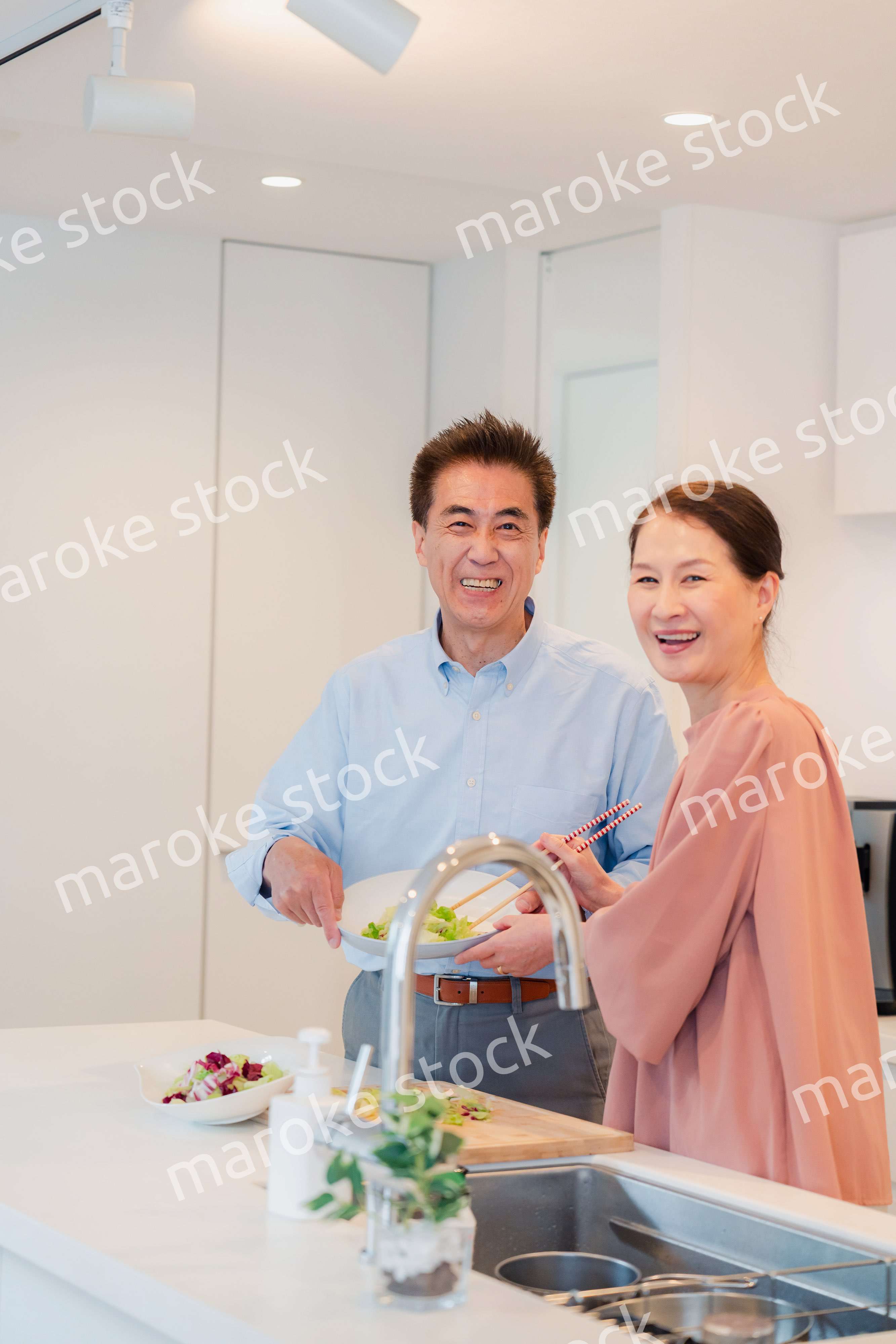 キッチンで一緒にクッキングを楽しむシニアの夫婦