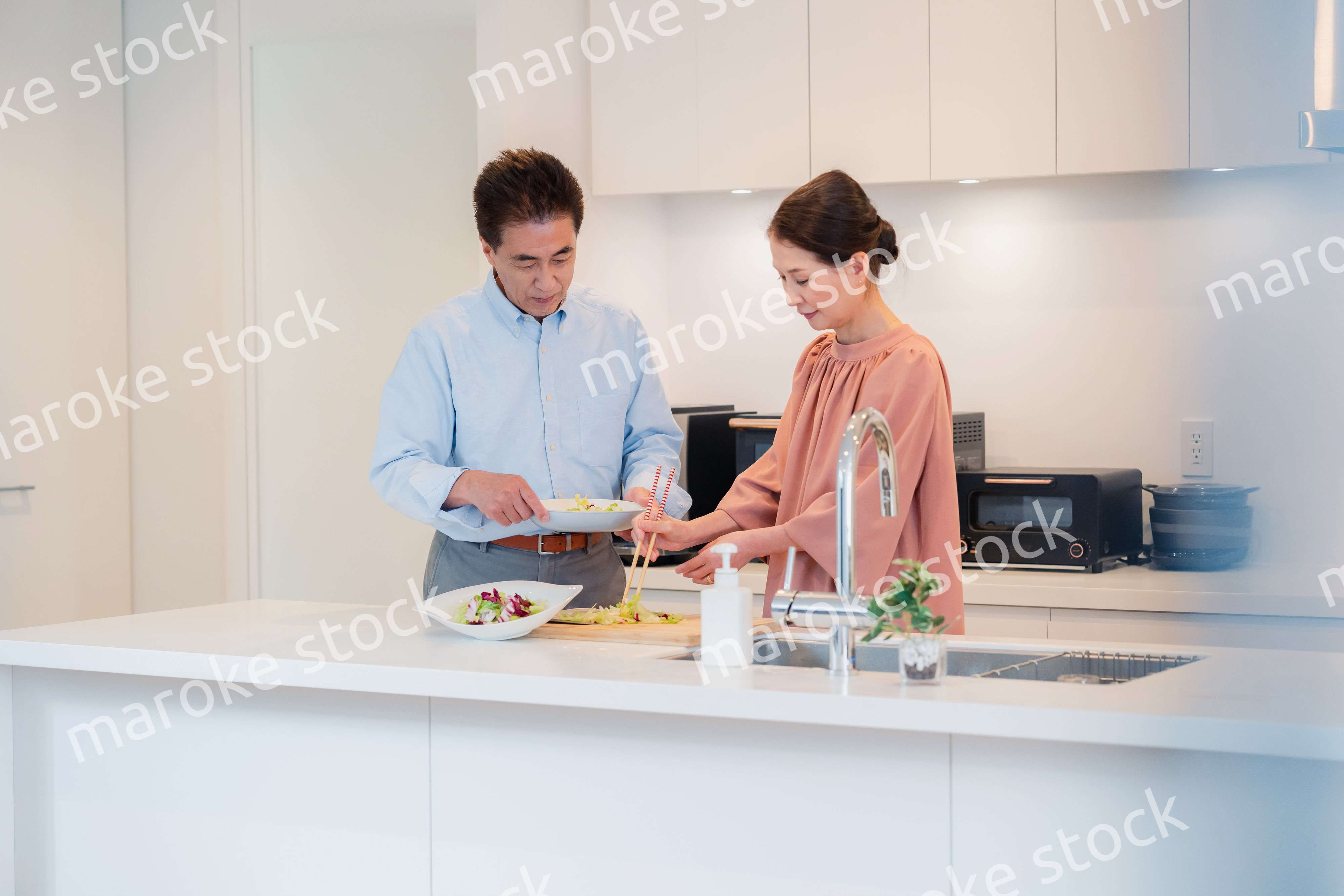 キッチンで一緒にクッキングを楽しむシニアの夫婦