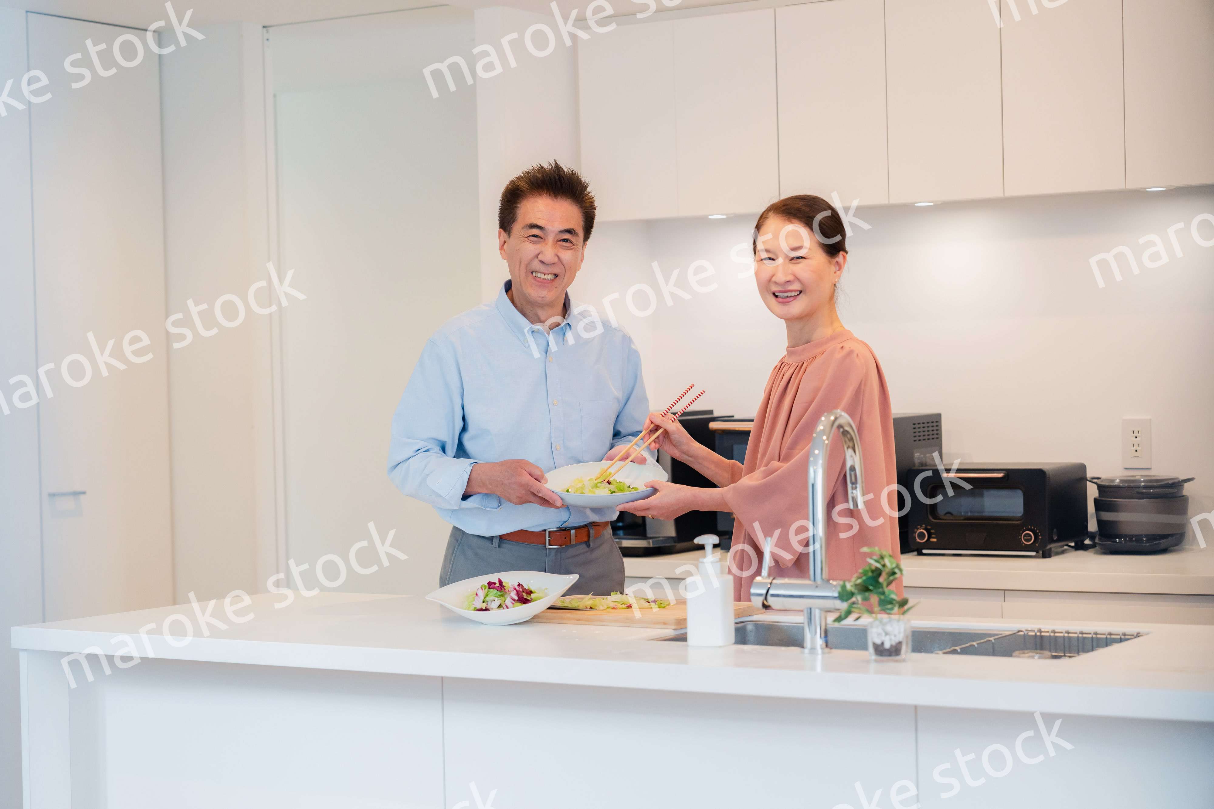 キッチンで一緒にクッキングを楽しむシニアの夫婦