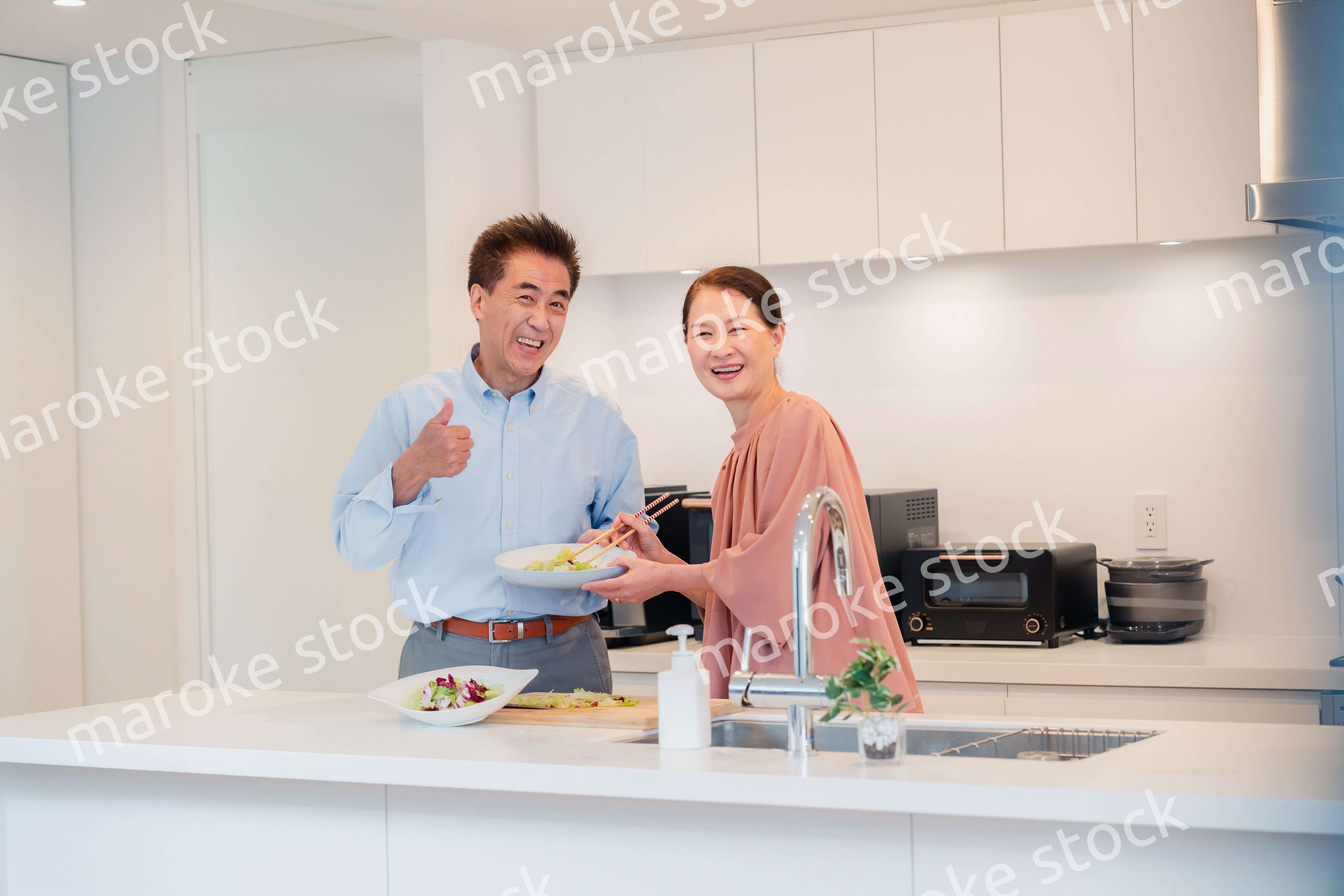 キッチンで一緒にクッキングを楽しむシニアの夫婦