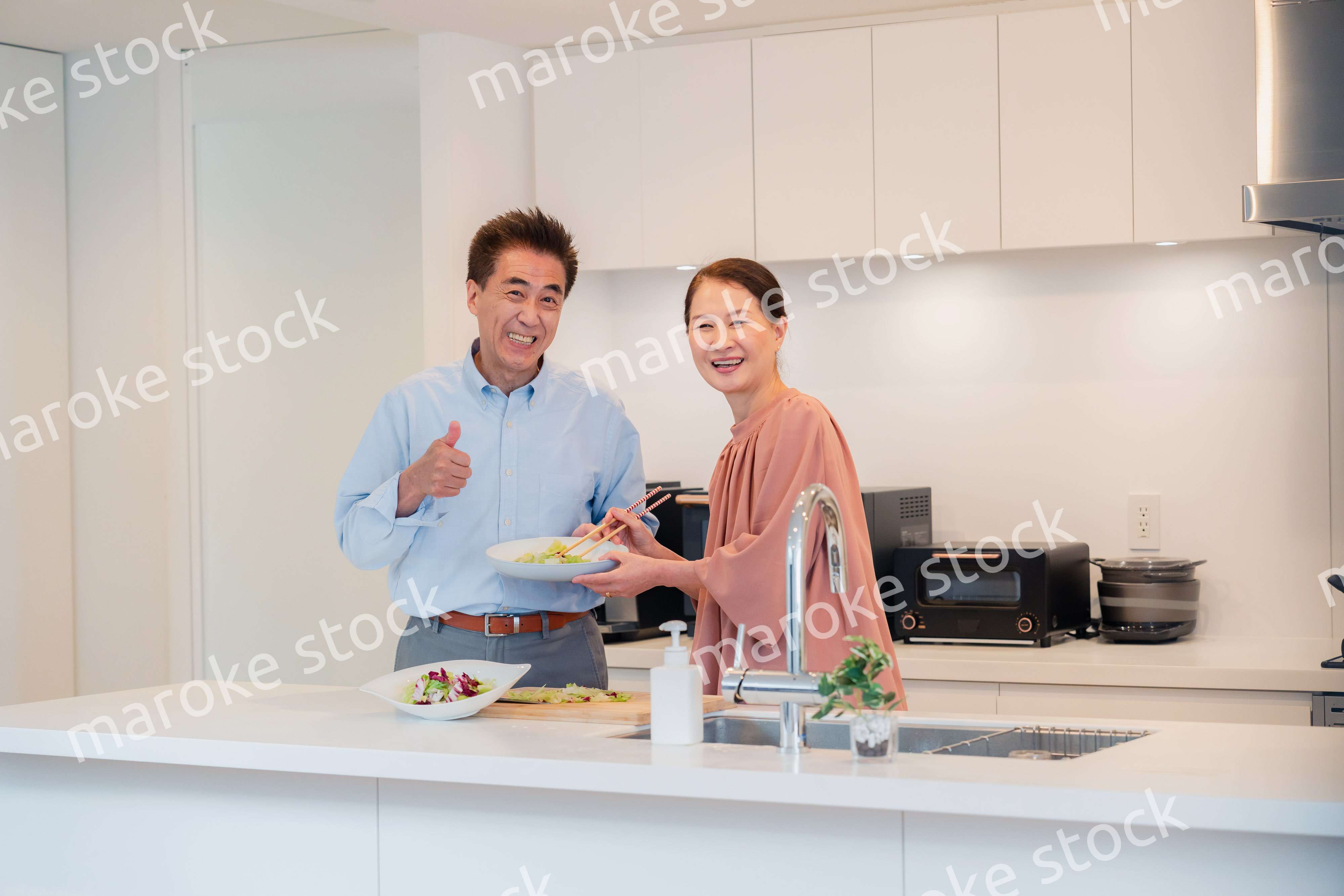 キッチンで一緒にクッキングを楽しむシニアの夫婦