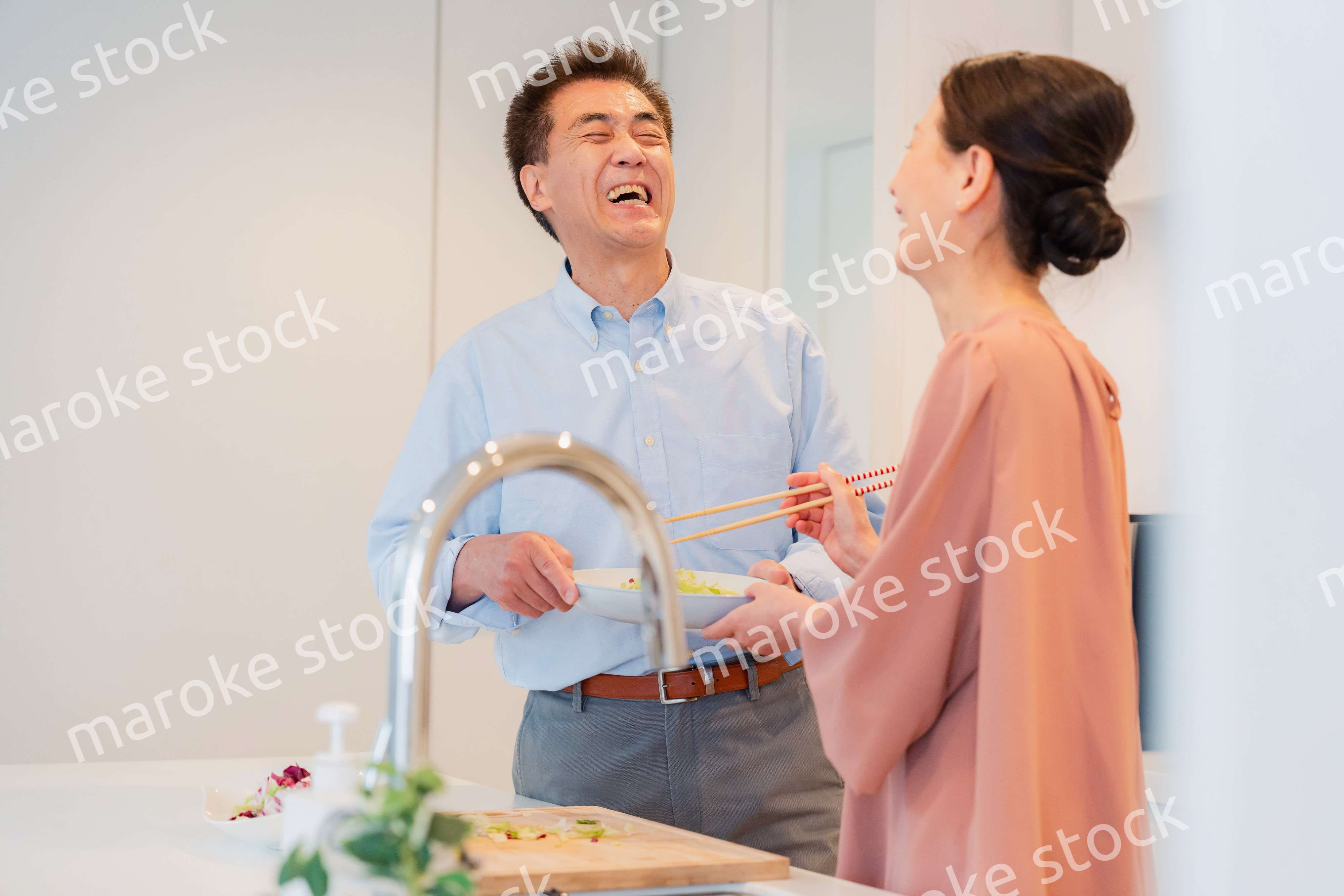 キッチンで一緒にクッキングを楽しむシニアの夫婦