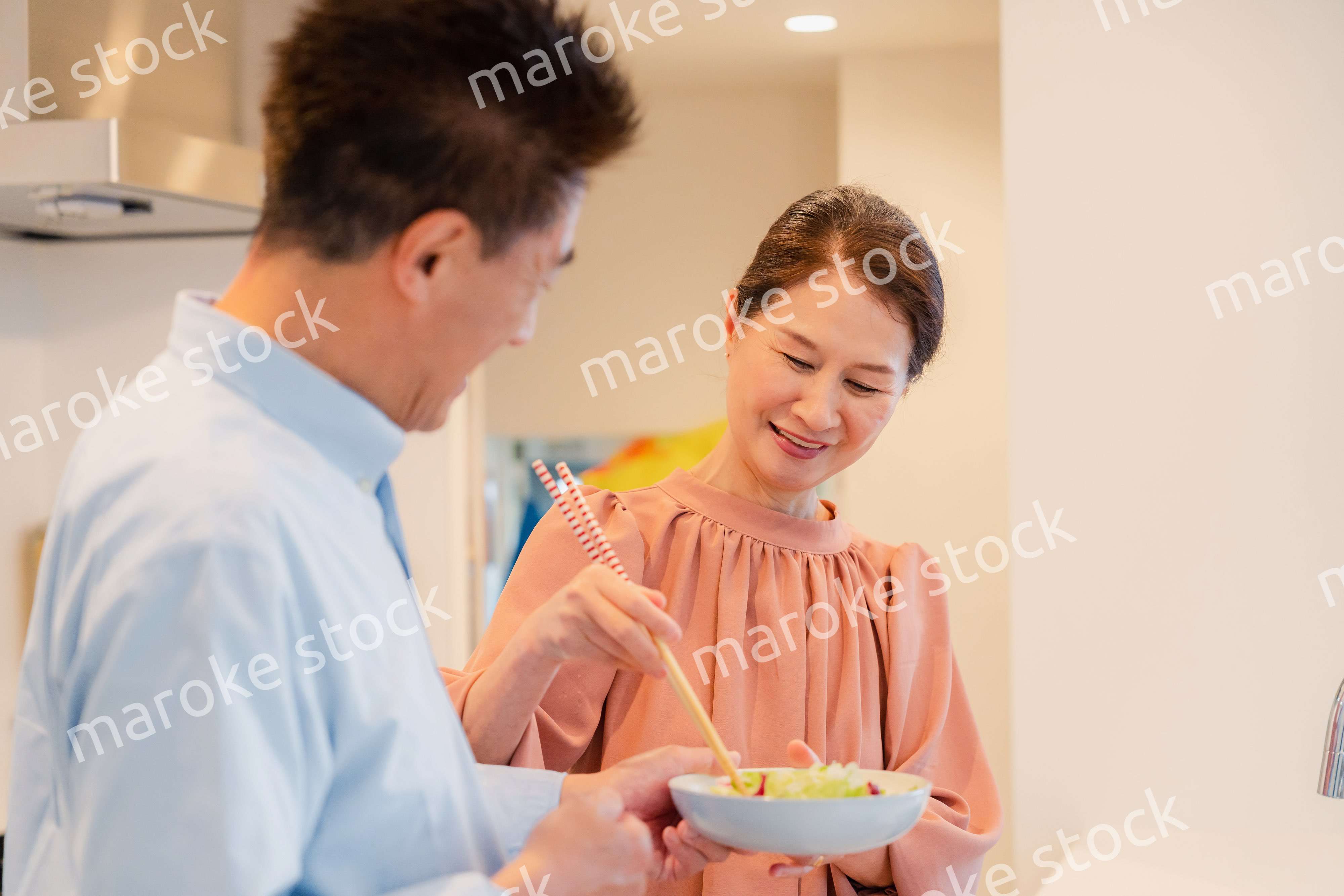 キッチンで一緒にクッキングを楽しむシニアの夫婦