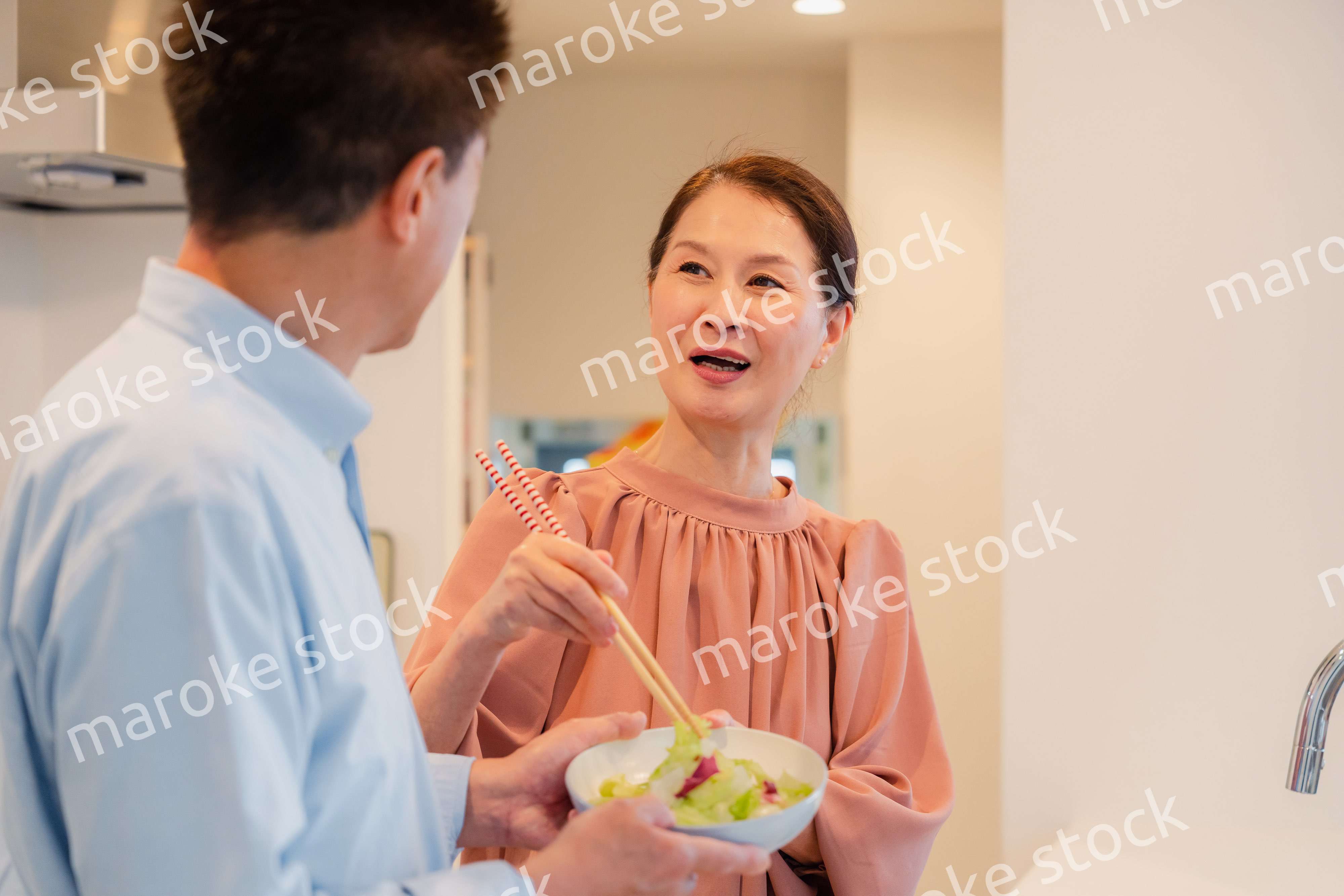 キッチンで一緒にクッキングを楽しむシニアの夫婦