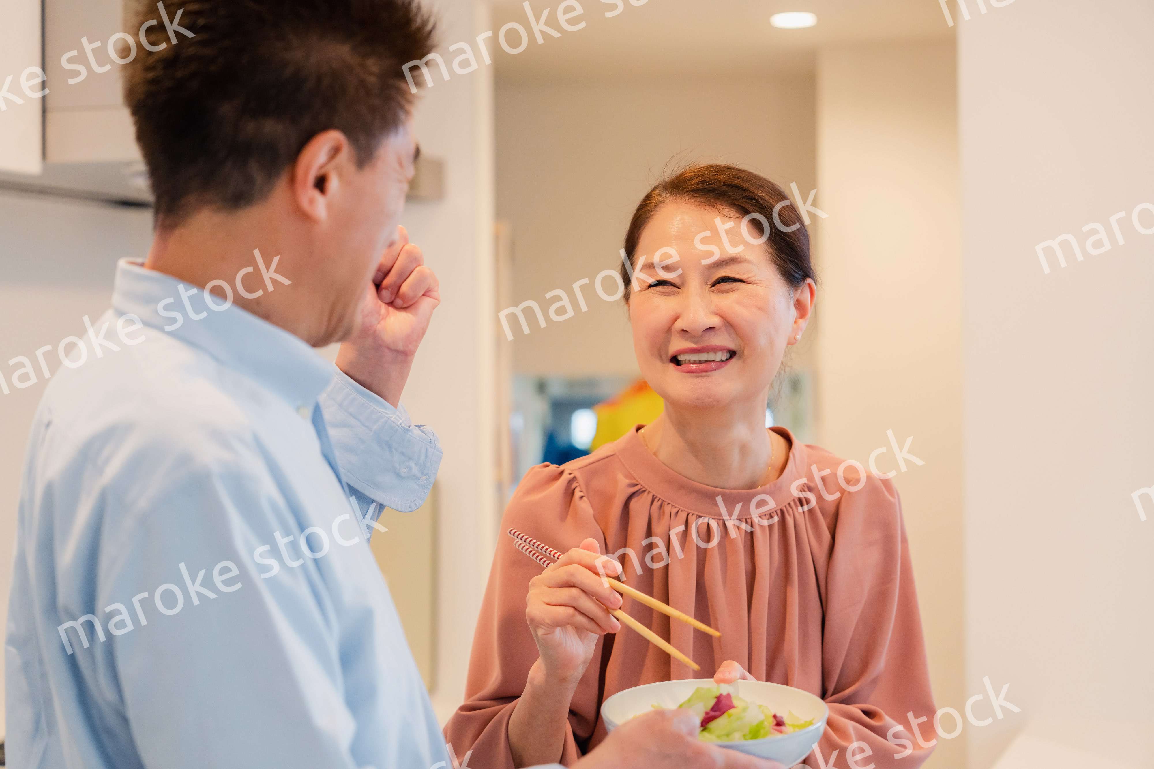 キッチンで一緒にクッキングを楽しむシニアの夫婦