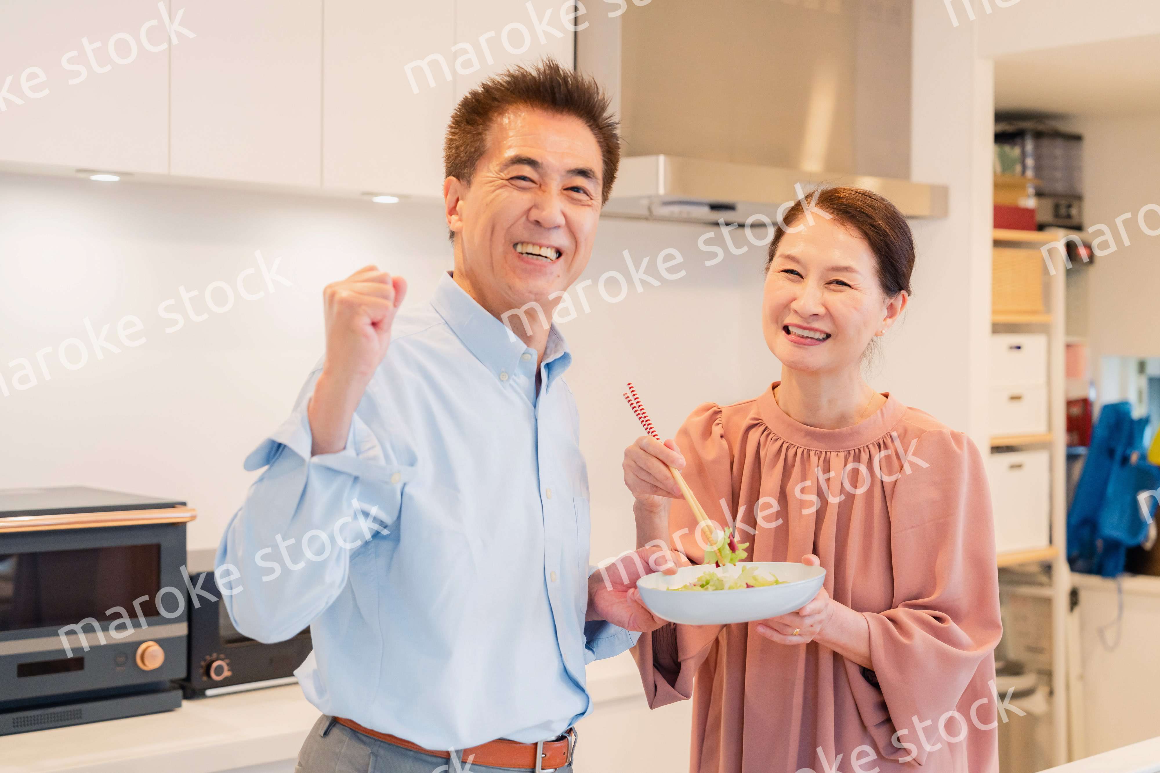 キッチンで一緒にクッキングを楽しむシニアの夫婦