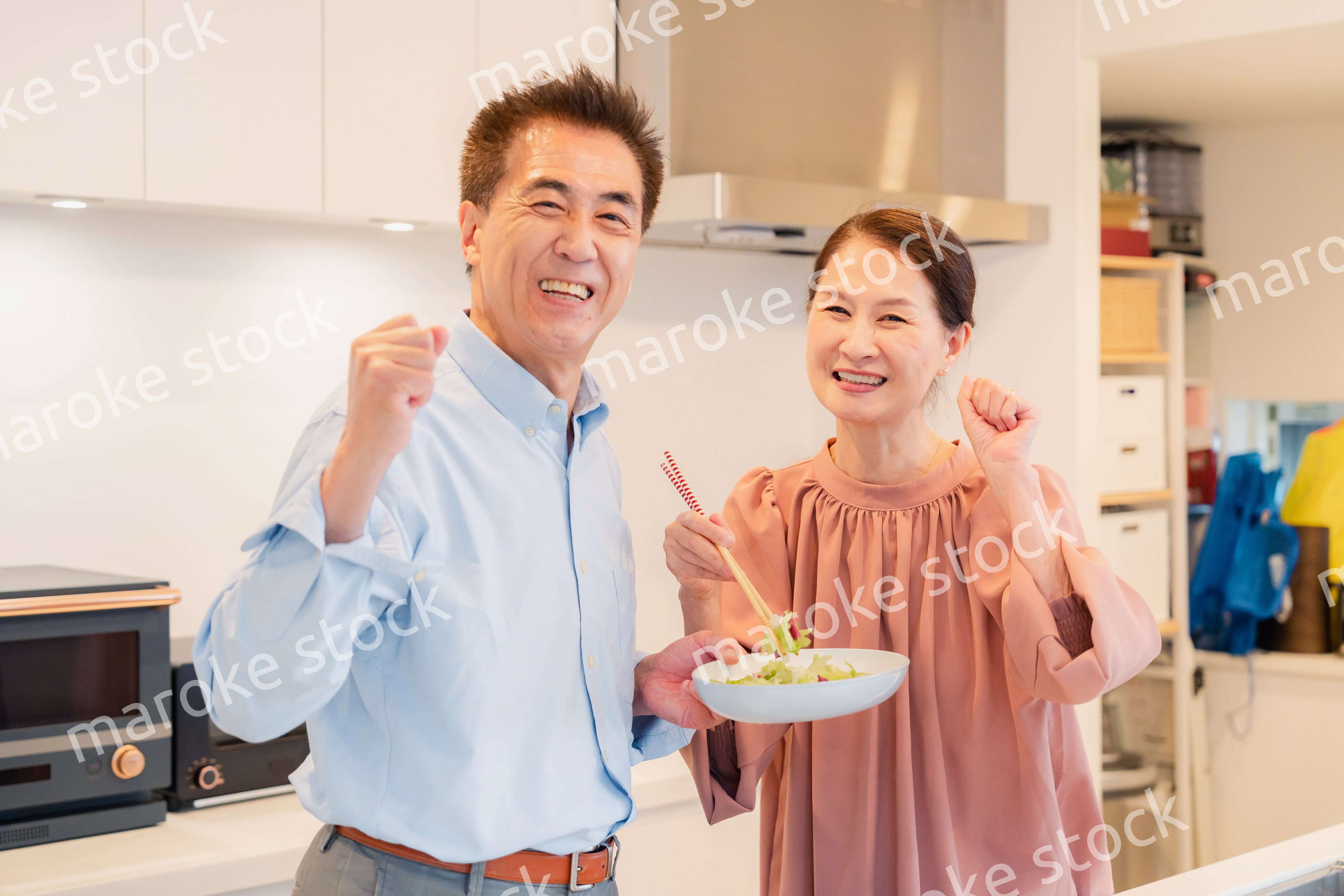 キッチンで一緒にクッキングを楽しむシニアの夫婦