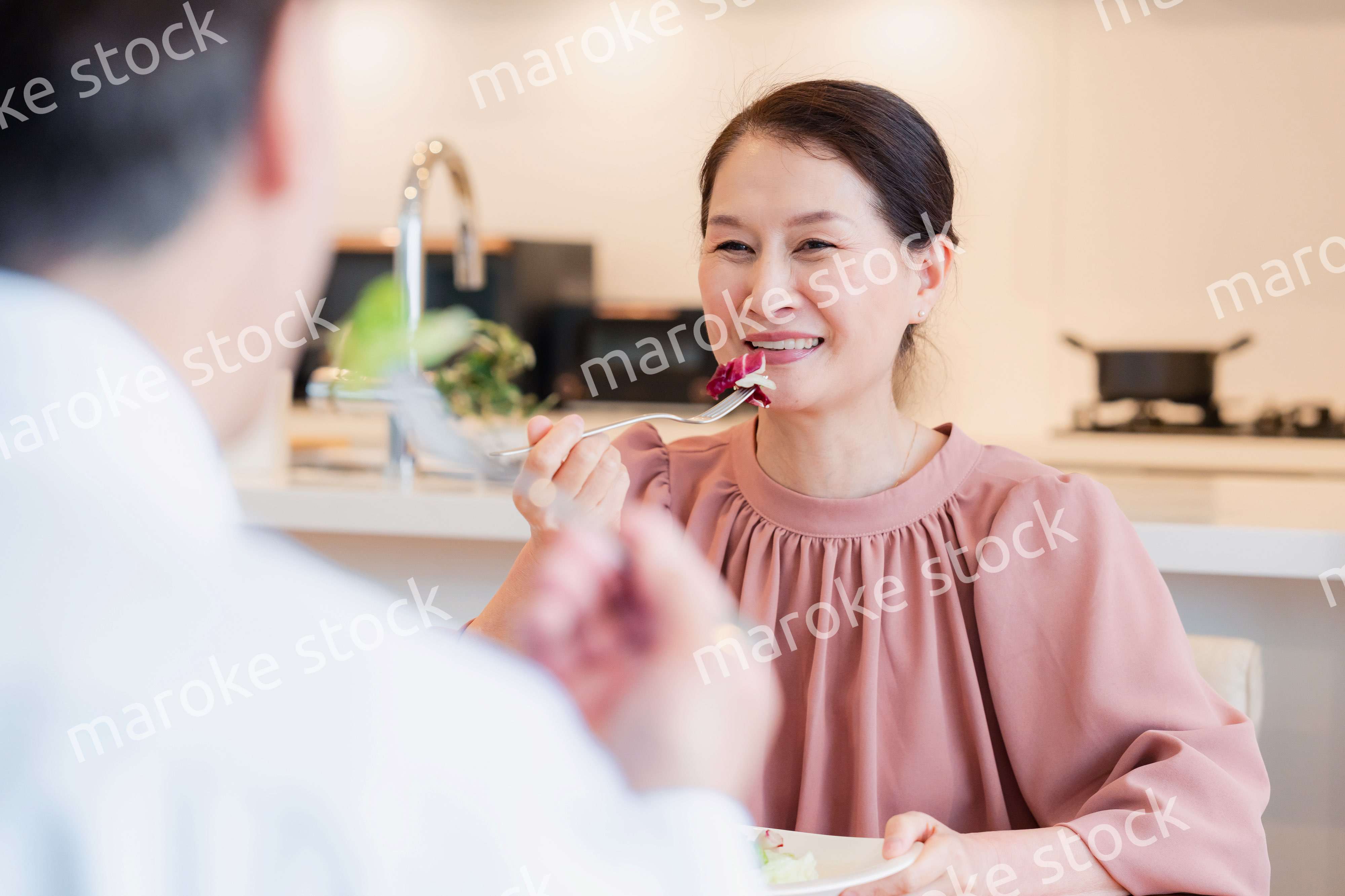 夫婦で楽しくご飯を食べる高齢女性